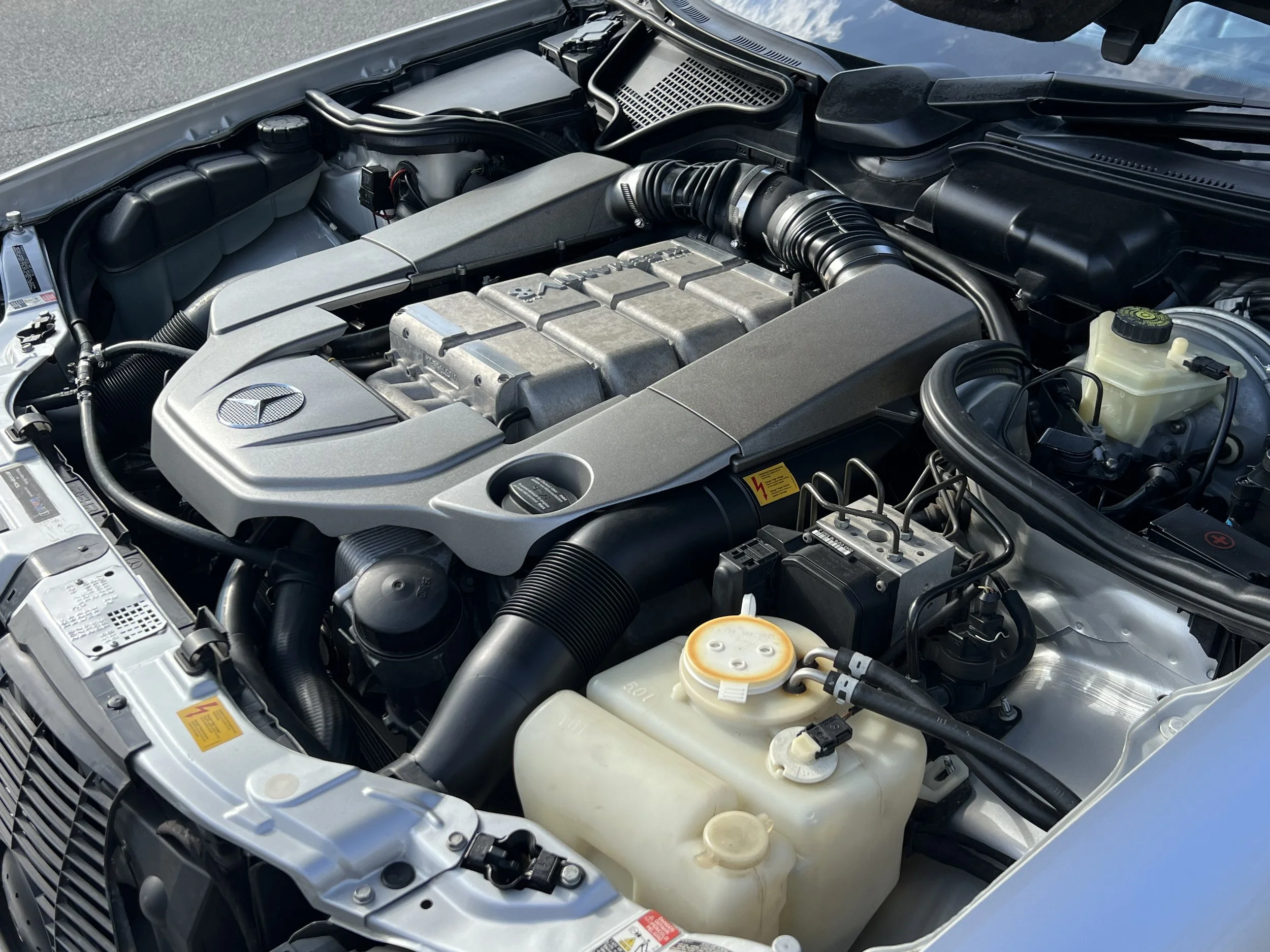 The image shows a close-up view of a clean Mercedes-Benz car engine inside the hood.