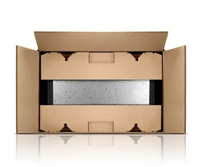 Corrugated shipping box lying on its side showing a die-cut corrugated protective insert.