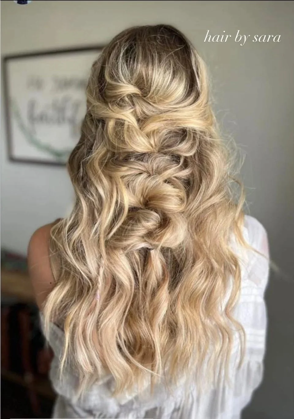 Back view of a woman with long, blonde, wavy hair styled in a loose braid with curls, with the text 'hair by sara' in the top right corner.