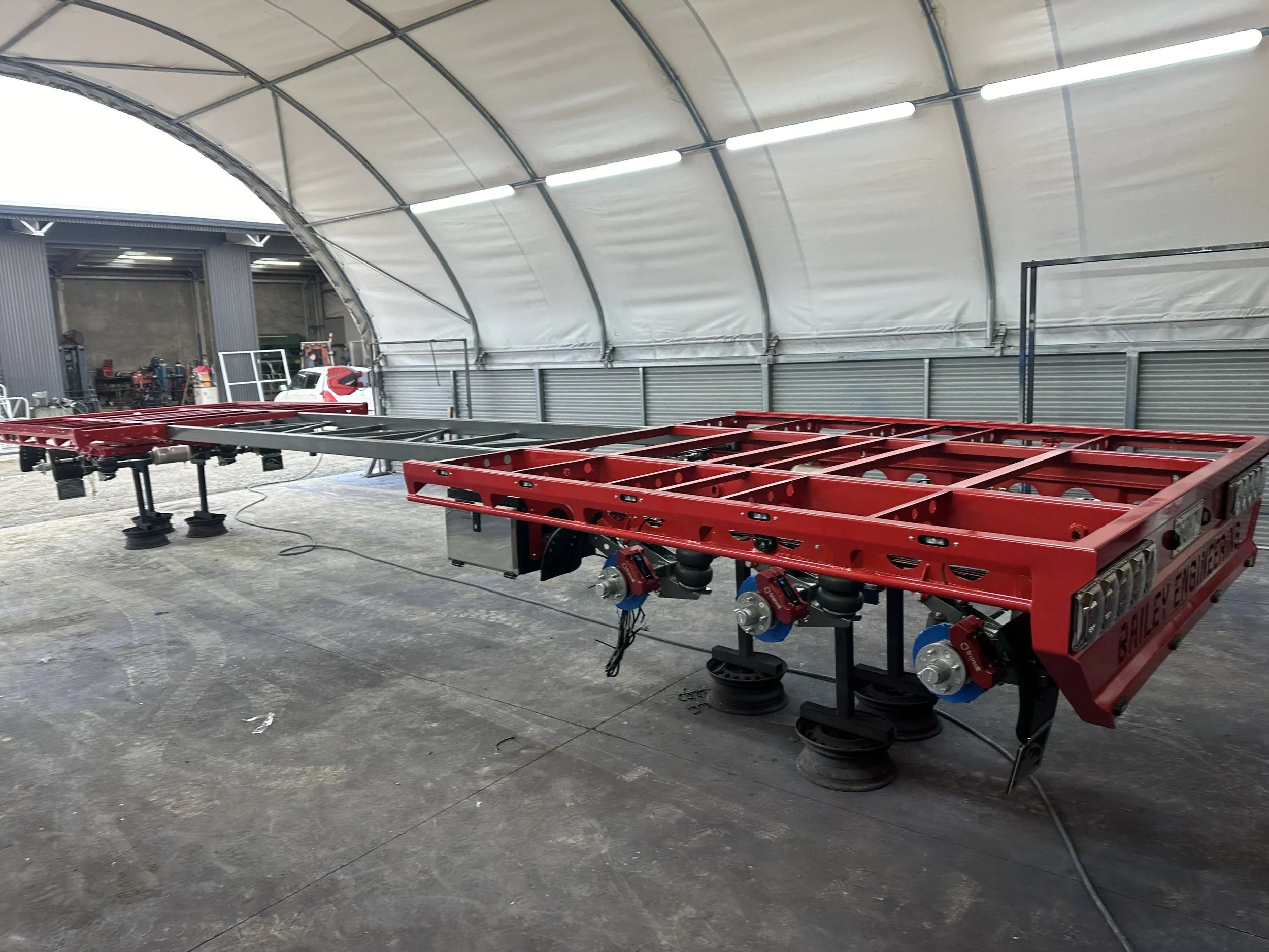 Red industrial trailer chassis in a workshop showcasing IGL Coatings for industrial applications. Provides superior protection against chemicals, corrosion, and environmental exposure, ensuring enhanced durability and performance.