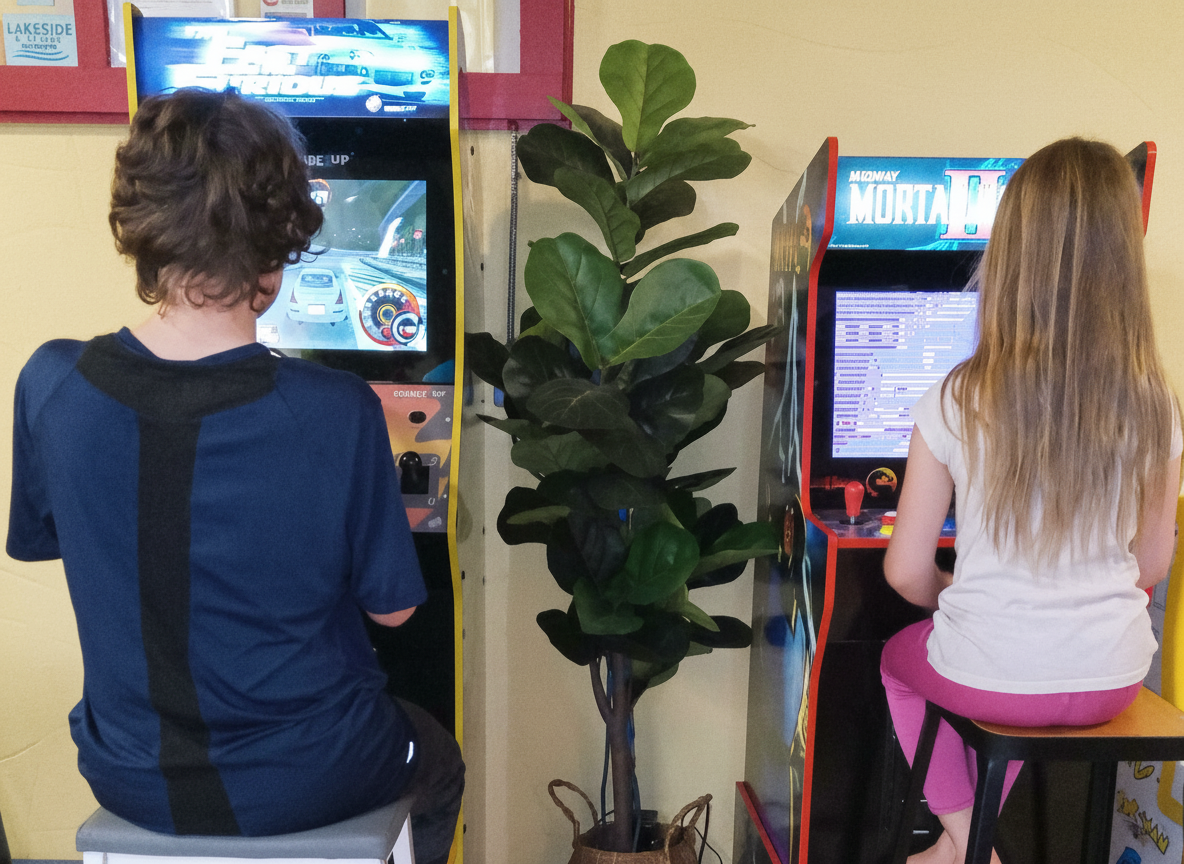 kids sitting at arcade cabinets playing