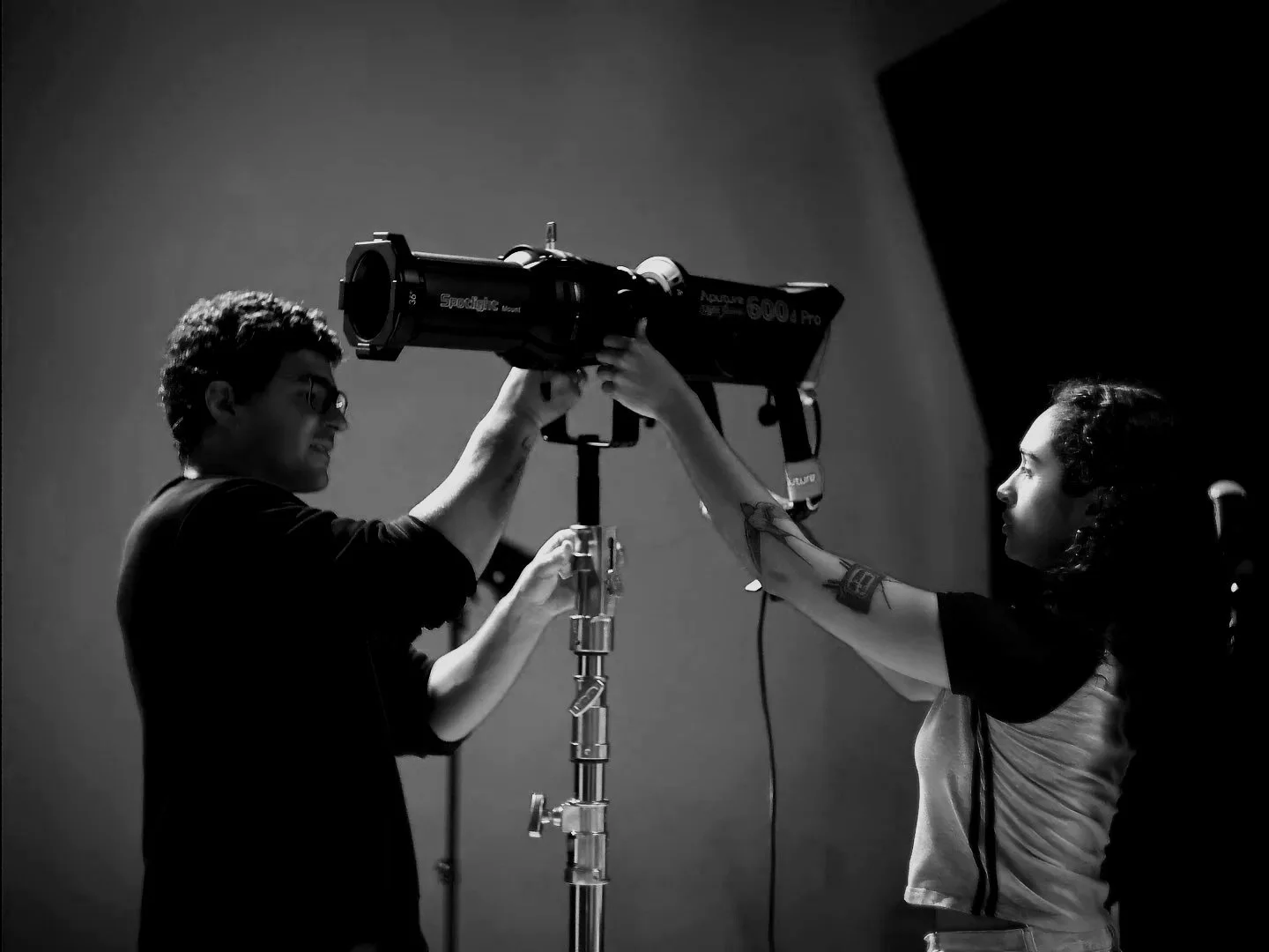 Two women working on a photoshoot with a large camera on a tripod in a studio, black and white.
