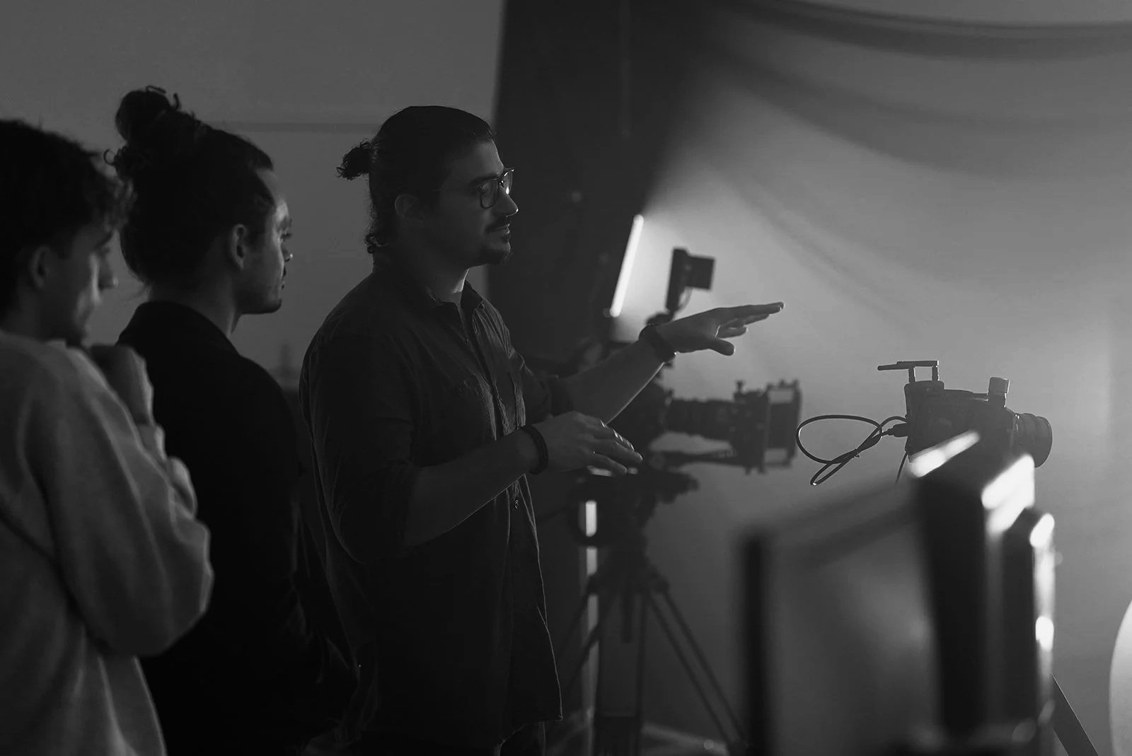 A group of people watching a person explaining a camera setup in a studio with professional filming equipment.