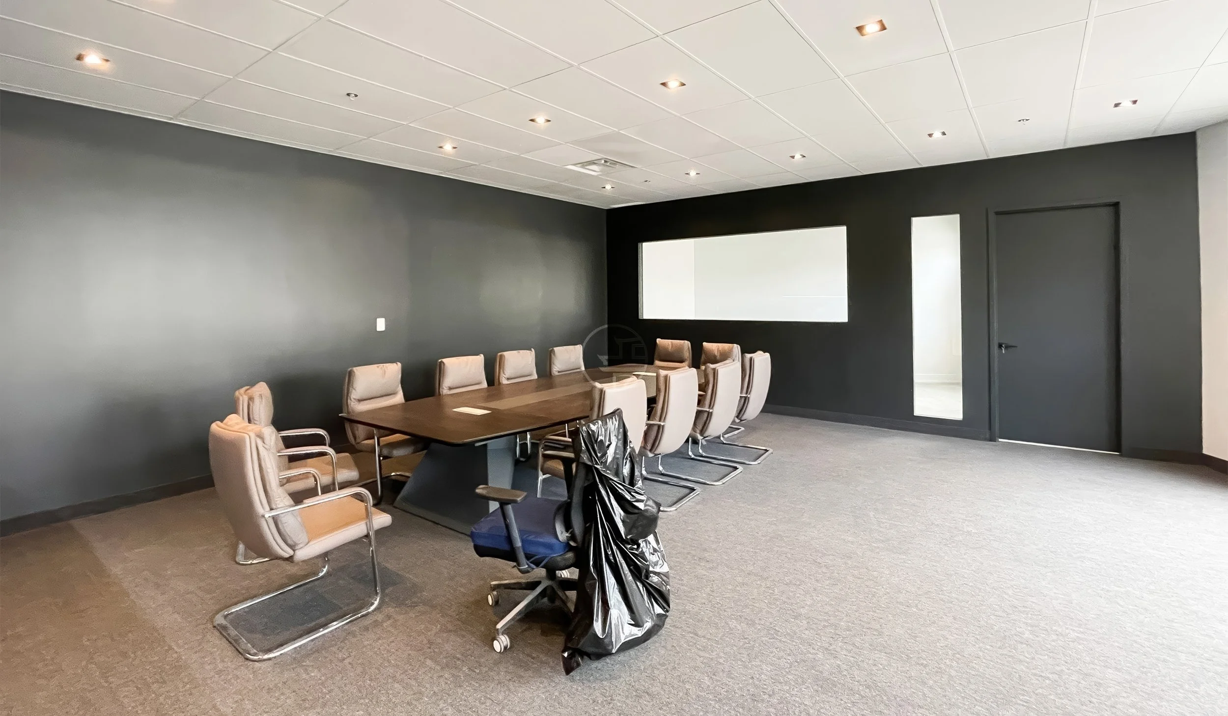 Commercial office conference room renovation in Toronto featuring modern meeting table, ergonomic chairs, and minimalist black accent wall design