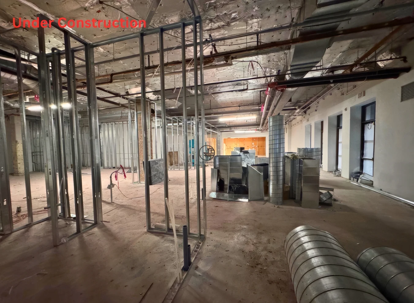 Commercial restaurant renovation under construction in Toronto with exposed steel framing, HVAC ducts, and interior build-out phase