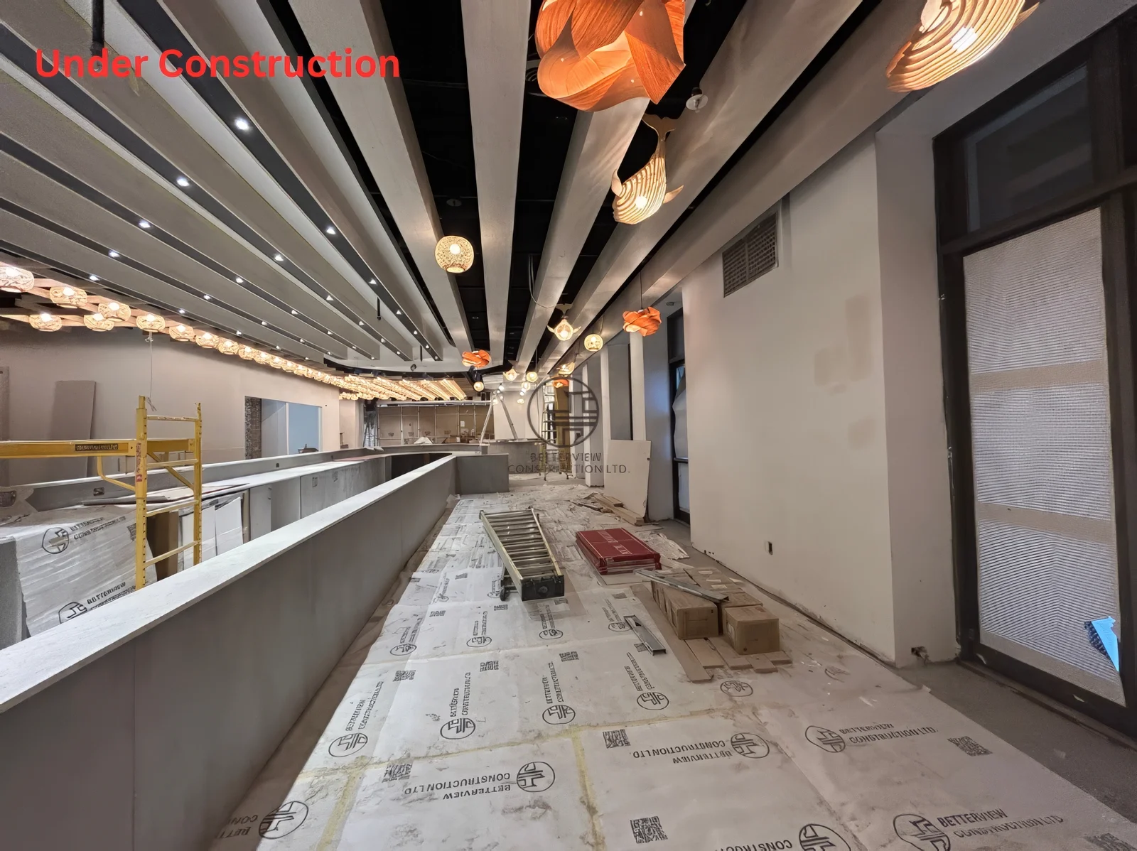 Restaurant renovation in Toronto featuring linear ceiling design, pendant lighting installation, and long dining bar layout under construction