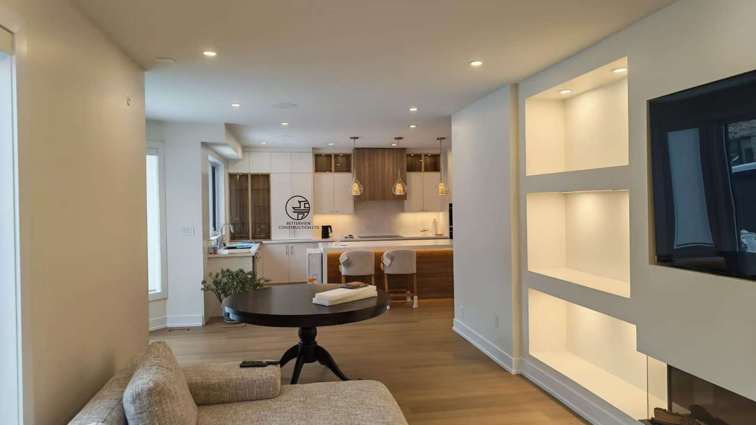 open concept living room and kitchen with built in wall unit shelving modern fireplace and wood flooring in Toronto home renovation