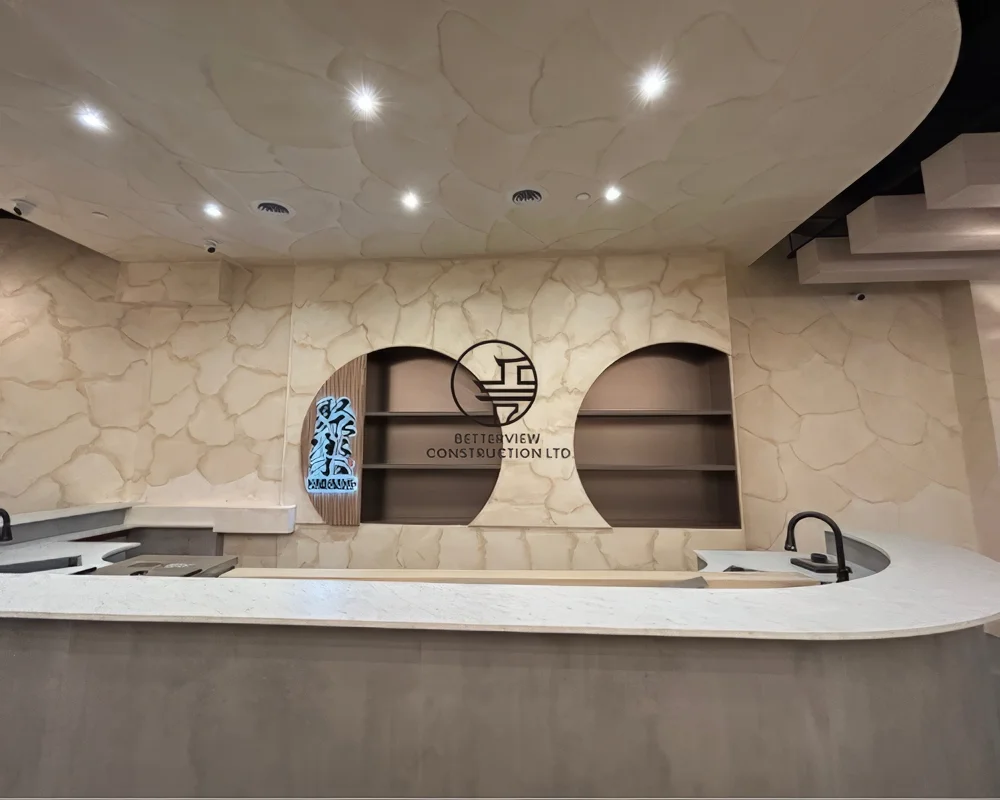 Custom restaurant bar counter and feature wall design in Toronto with curved countertop, textured wall finish, and built-in shelving