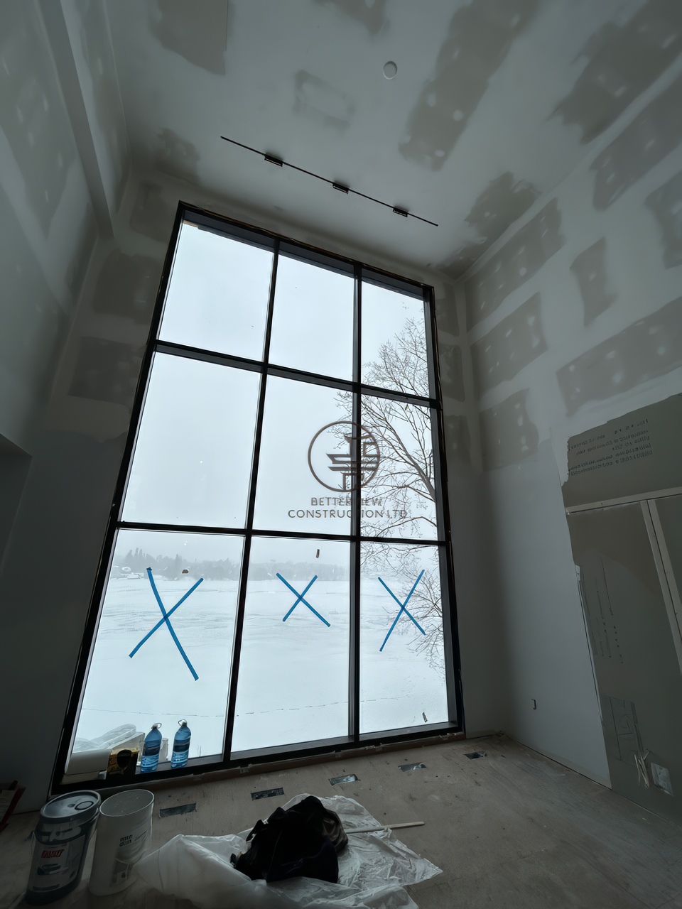 Interior renovation with drywall installation and large floor to ceiling window, modern open space under construction