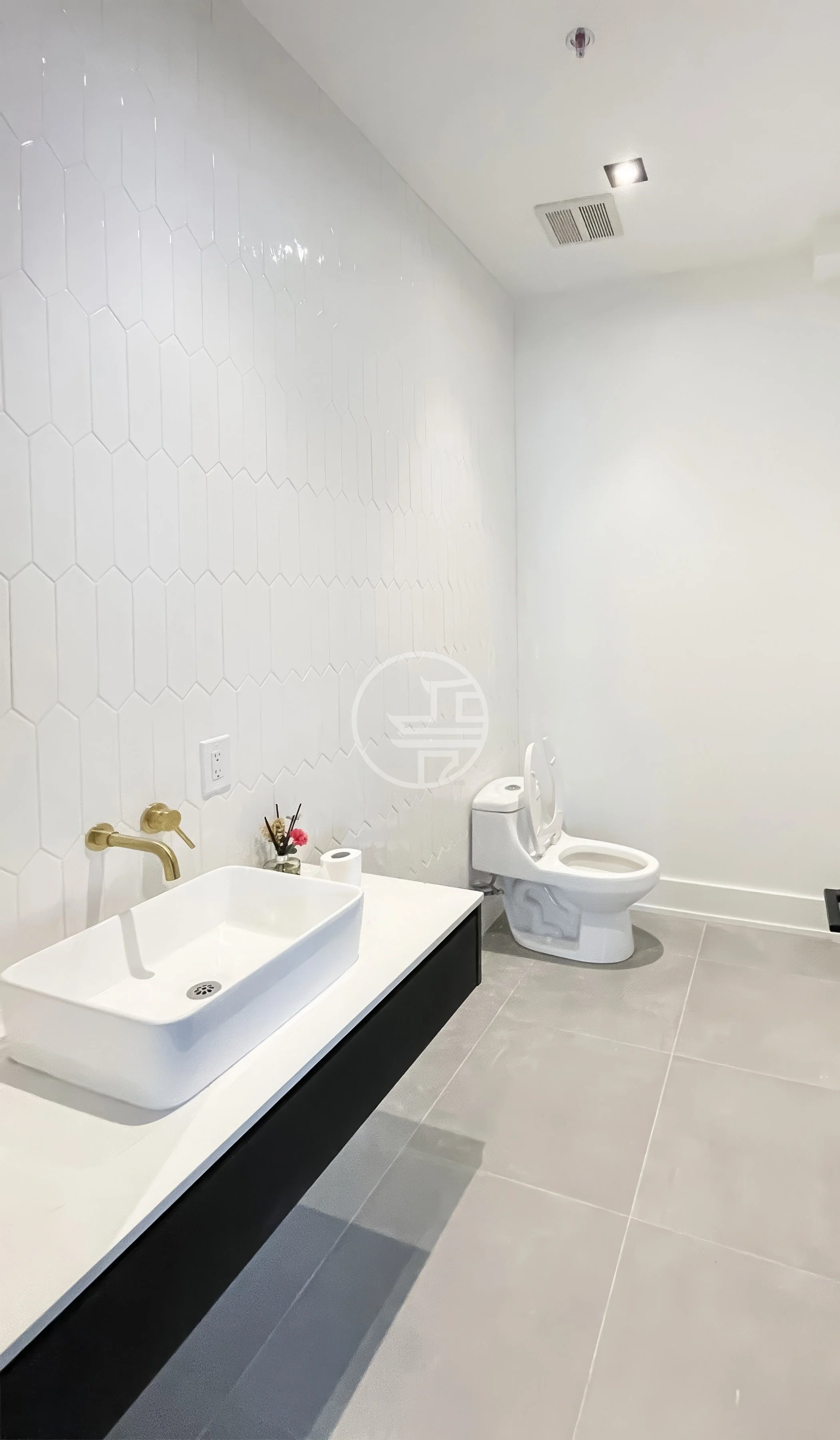 Modern commercial bathroom renovation in Toronto featuring white tile wall, vessel sink, gold faucet, and minimalist washroom design