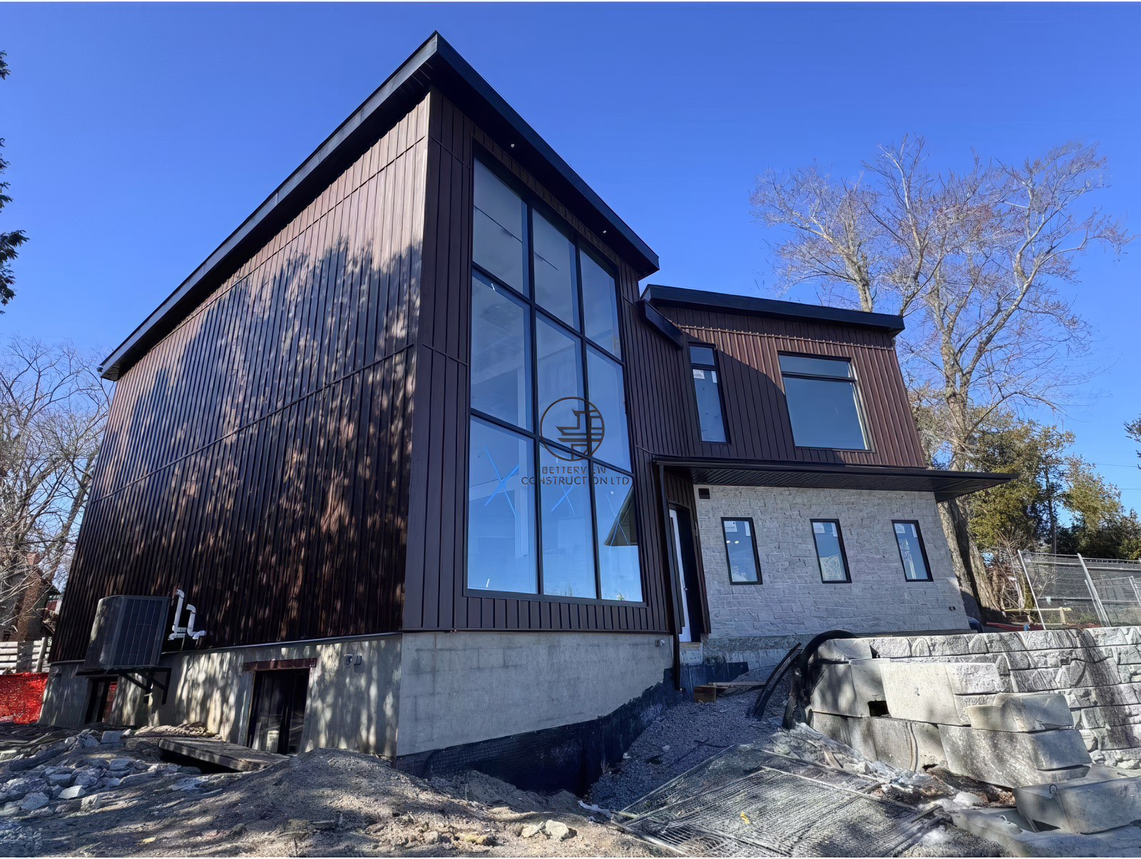 Modern home exterior with floor to ceiling windows, wood siding and stone facade, custom renovation project