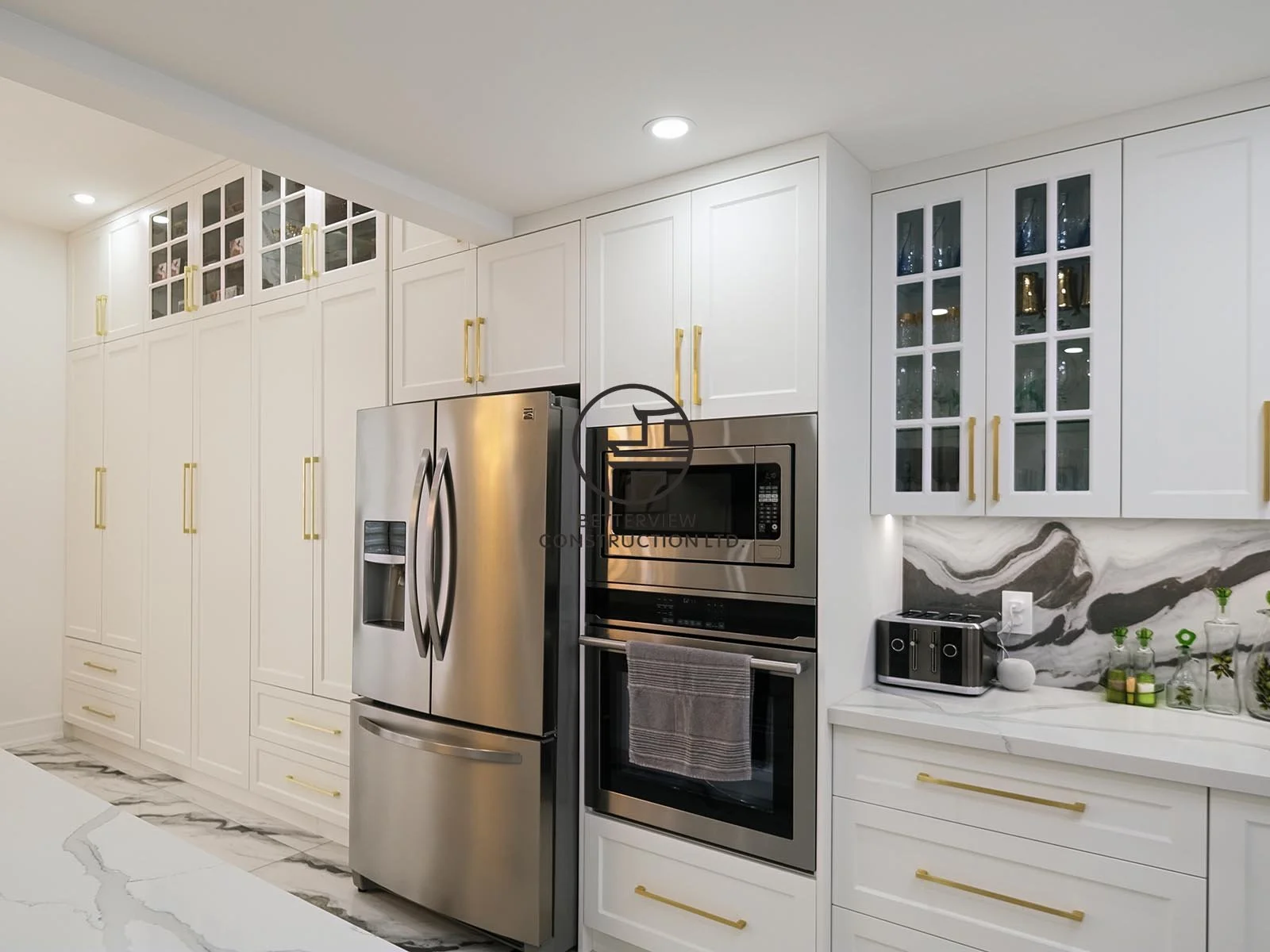 This custom kitchen features full-height white shaker cabinetry, integrated pantry storage, built-in appliances, and quartz countertops, maximizing both functionality and timeless style.