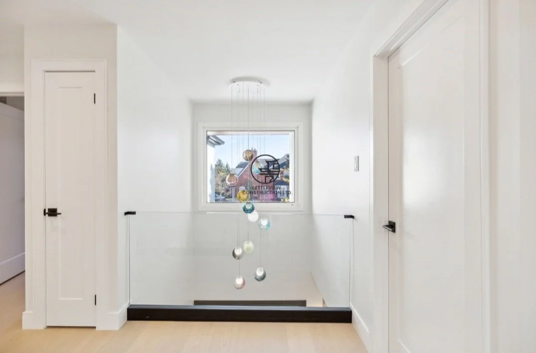 Modern upstairs hallway renovation featuring a glass guardrail, custom pendant lighting, and clean minimalist interior design in a GTA home