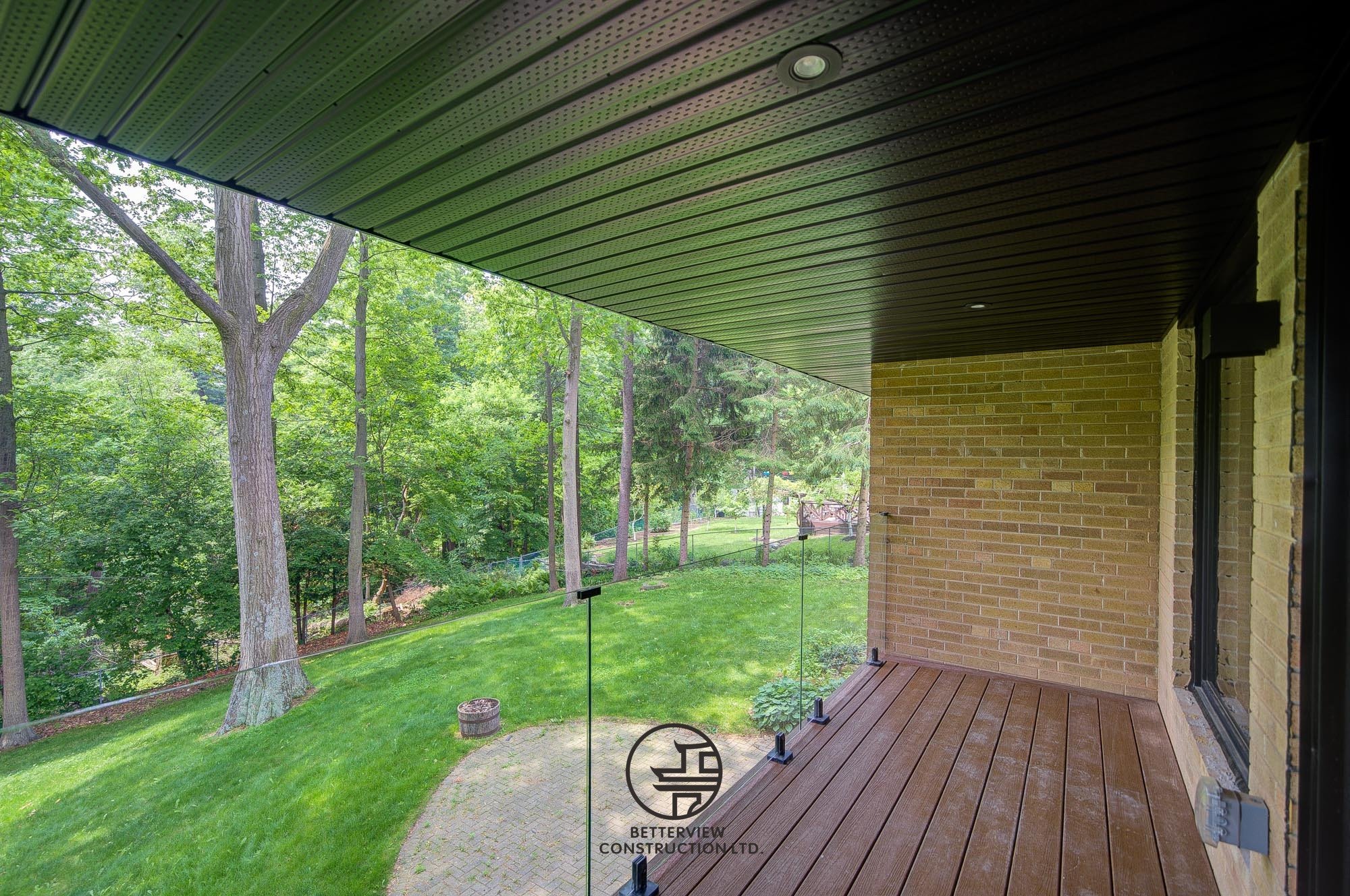 modern backyard deck with glass railing and garden view