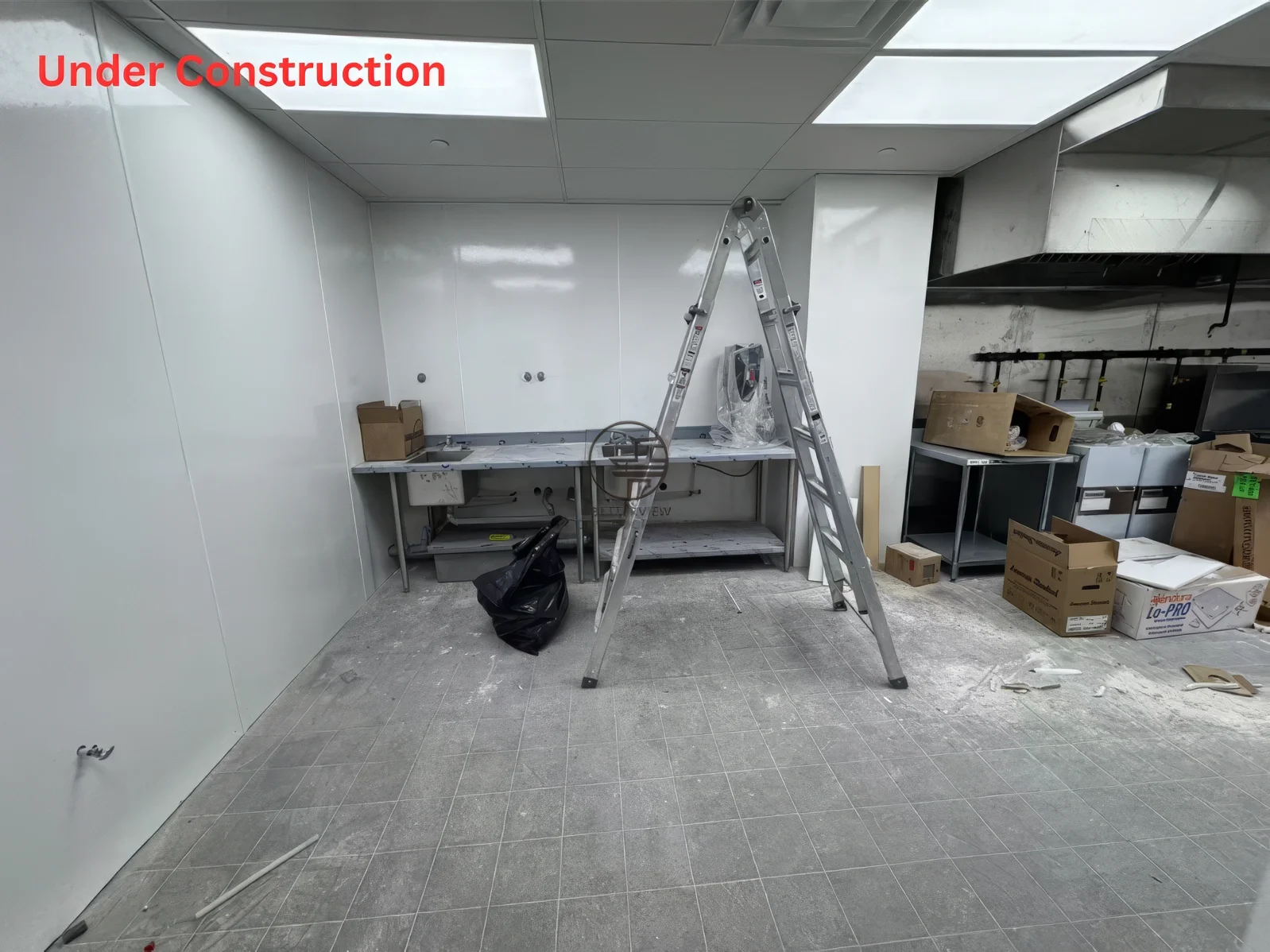 Commercial kitchen installation during restaurant renovation in Toronto with stainless steel workstations, ventilation system, and food prep area setup