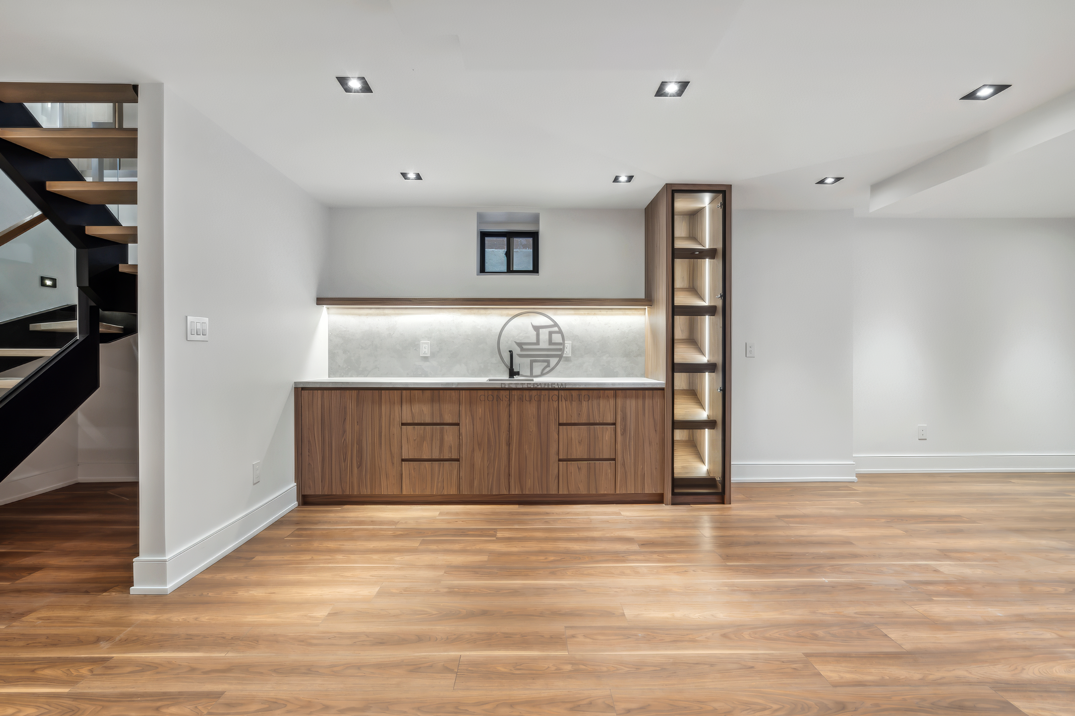 Finished basement with built-in bar, custom wood cabinetry, open floor space, and recessed lighting in a modern home renovation project