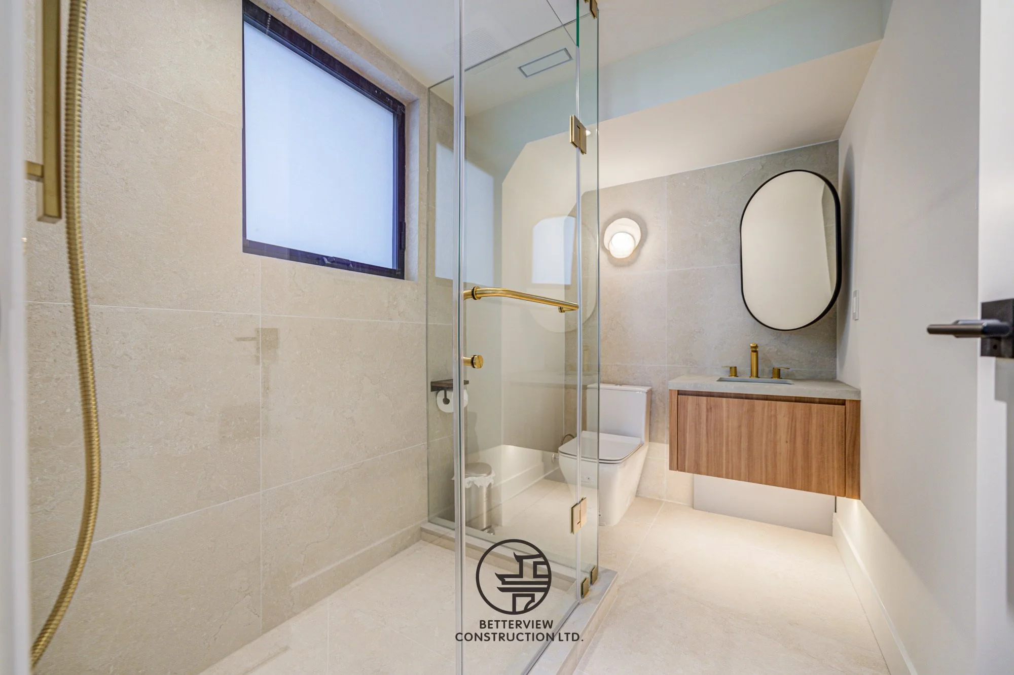 modern bathroom renovation with glass shower enclosure floating wood vanity and gold fixtures