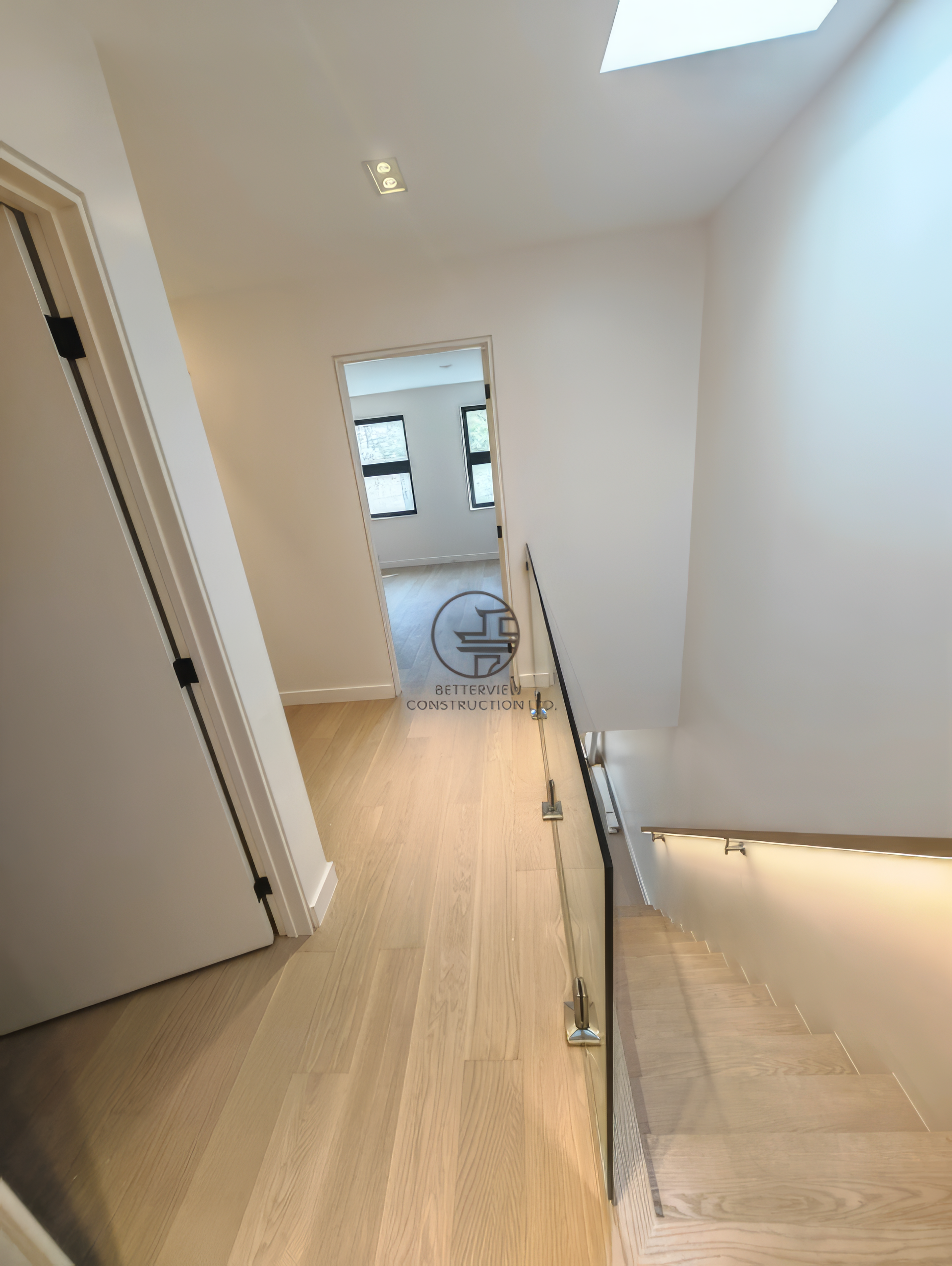 modern staircase with glass railing, light wood steps, and minimalist hallway design