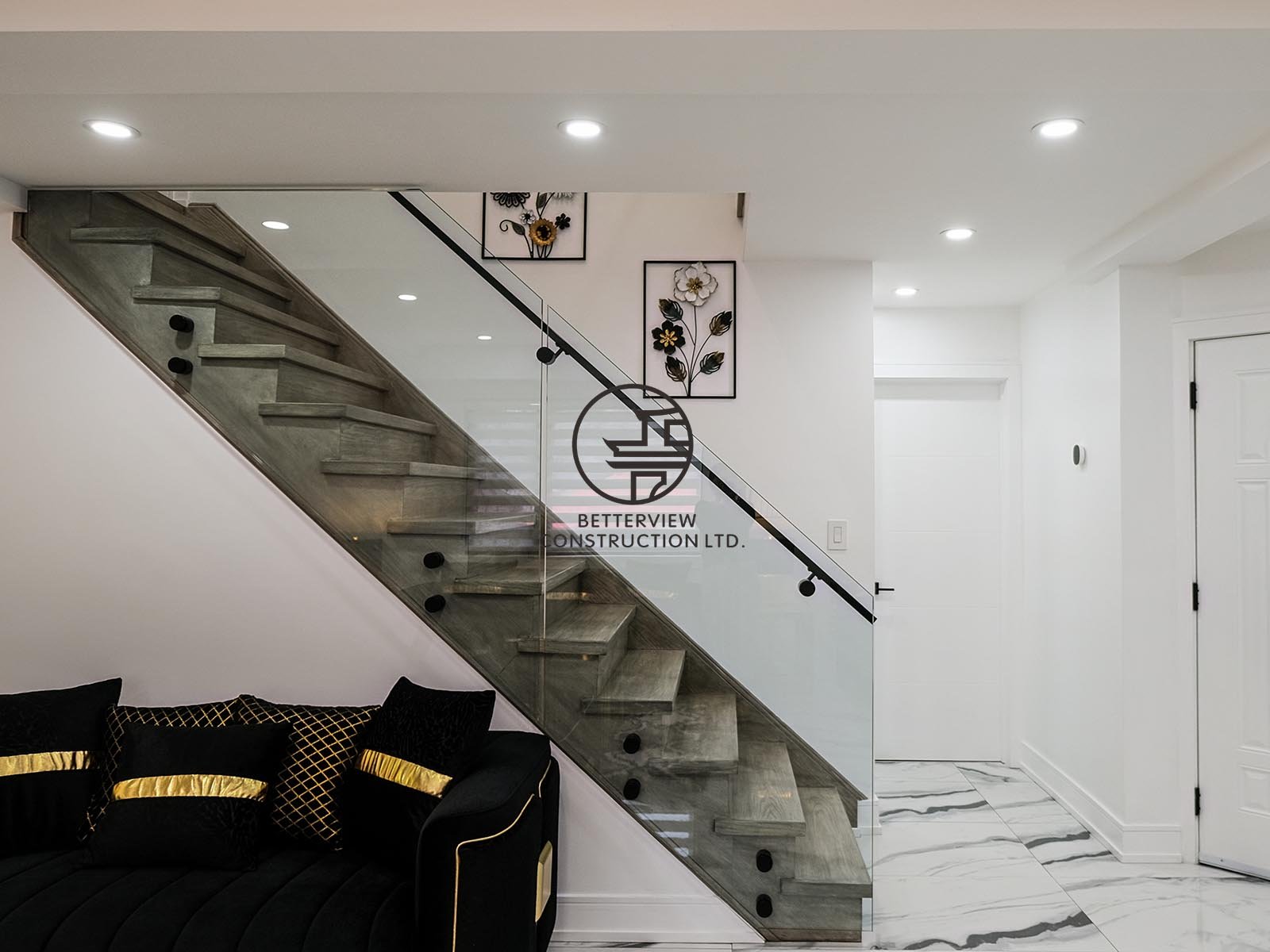 The glass-railed staircase seamlessly connects the living spaces while adding a sleek, modern aesthetic and maximizing the home's open-concept layout.