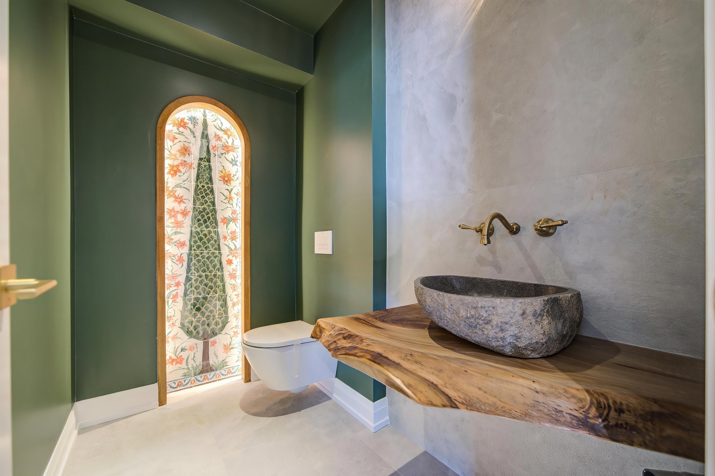 Custom powder room renovation featuring a natural stone vessel sink, live-edge wood vanity, arched decorative door panel, and bespoke interior finishes in a GTA home