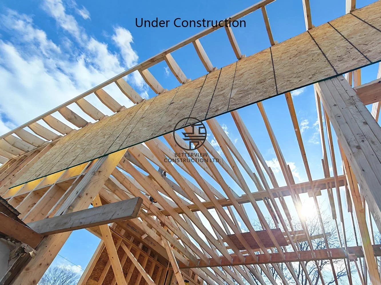 Engineered roof framing and wood truss installation for a custom home addition, highlighting structural carpentry and residential construction.