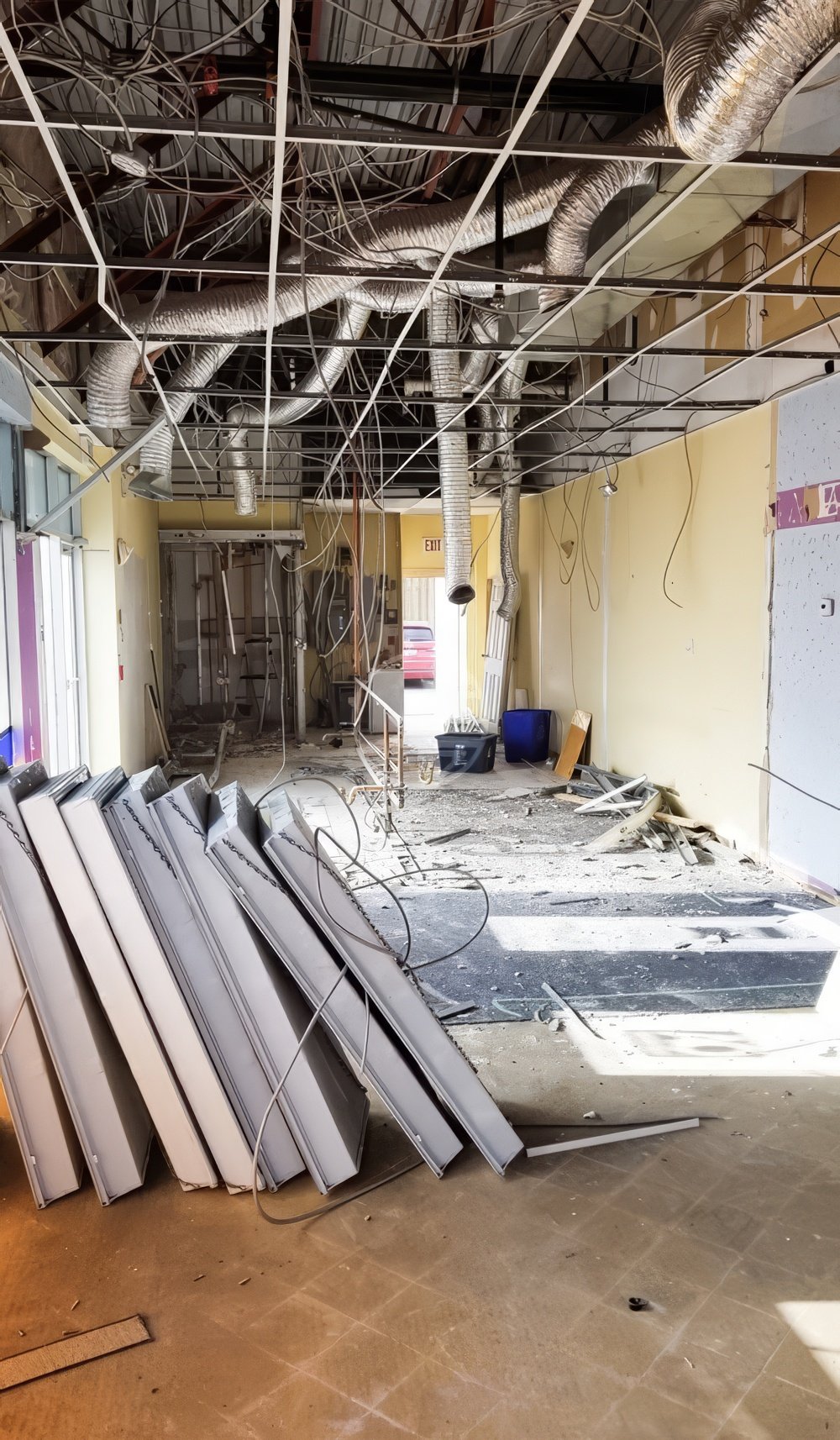 Commercial retail space demolition in Toronto showing ceiling strip-out, exposed wiring, HVAC ducts, and interior renovation preparation