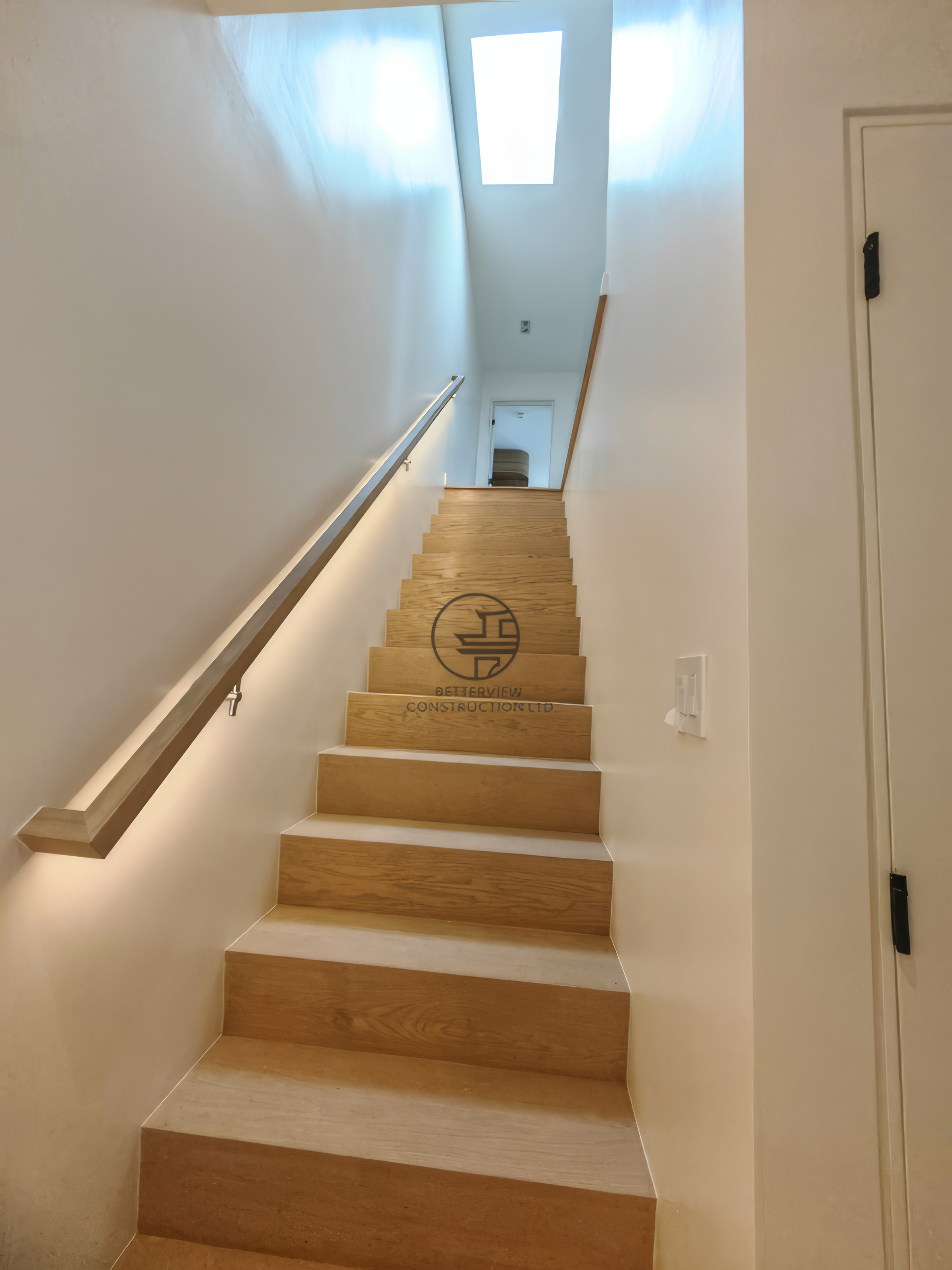 modern staircase with wood steps, minimalist handrail, and skylight lighting in residential renovation