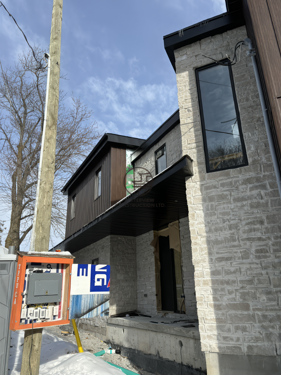 Modern home exterior renovation with stone facade, large windows and second floor addition near completion