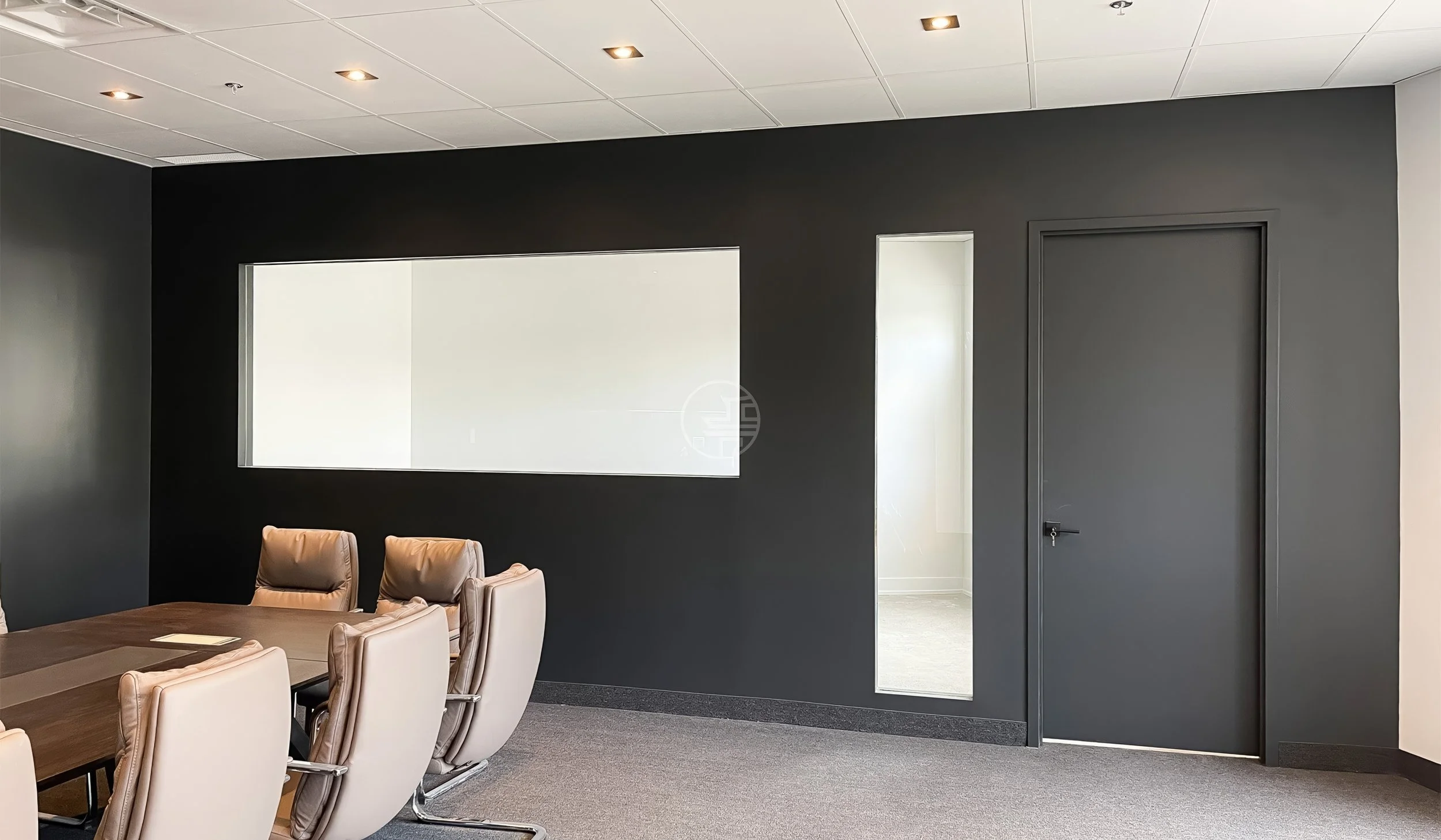 Modern office meeting room renovation in Toronto featuring conference table, glass viewing window, and minimalist black accent wall design