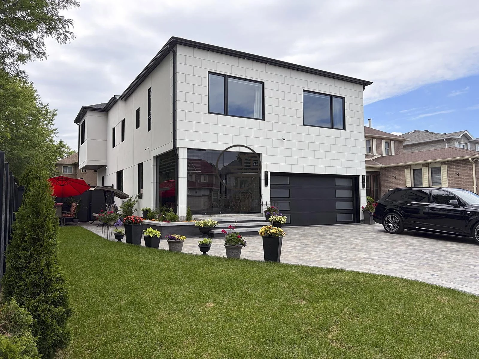 A wide-angle view showcases the completed home addition with its modern exterior finishes, landscaped front yard, and spacious driveway, creating a balanced and cohesive appearance.