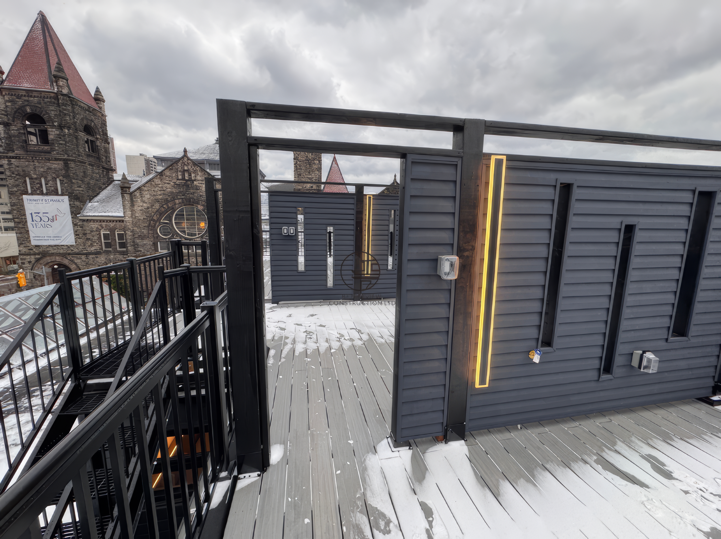 modern rooftop deck with privacy wall, vertical LED lighting, and composite decking in winter