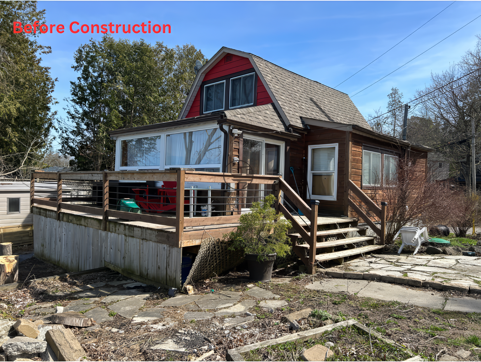 Before construction view of small detached house with wooden deck and exterior stairs in residential Toronto neighborhood