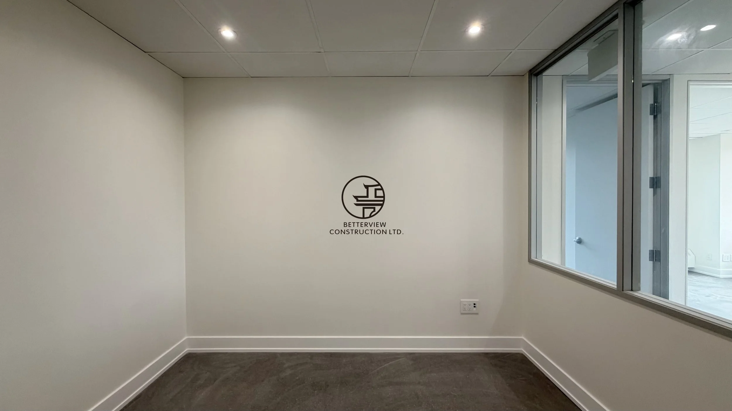 Private office room with interior glass window, recessed lighting, and modern commercial renovation design