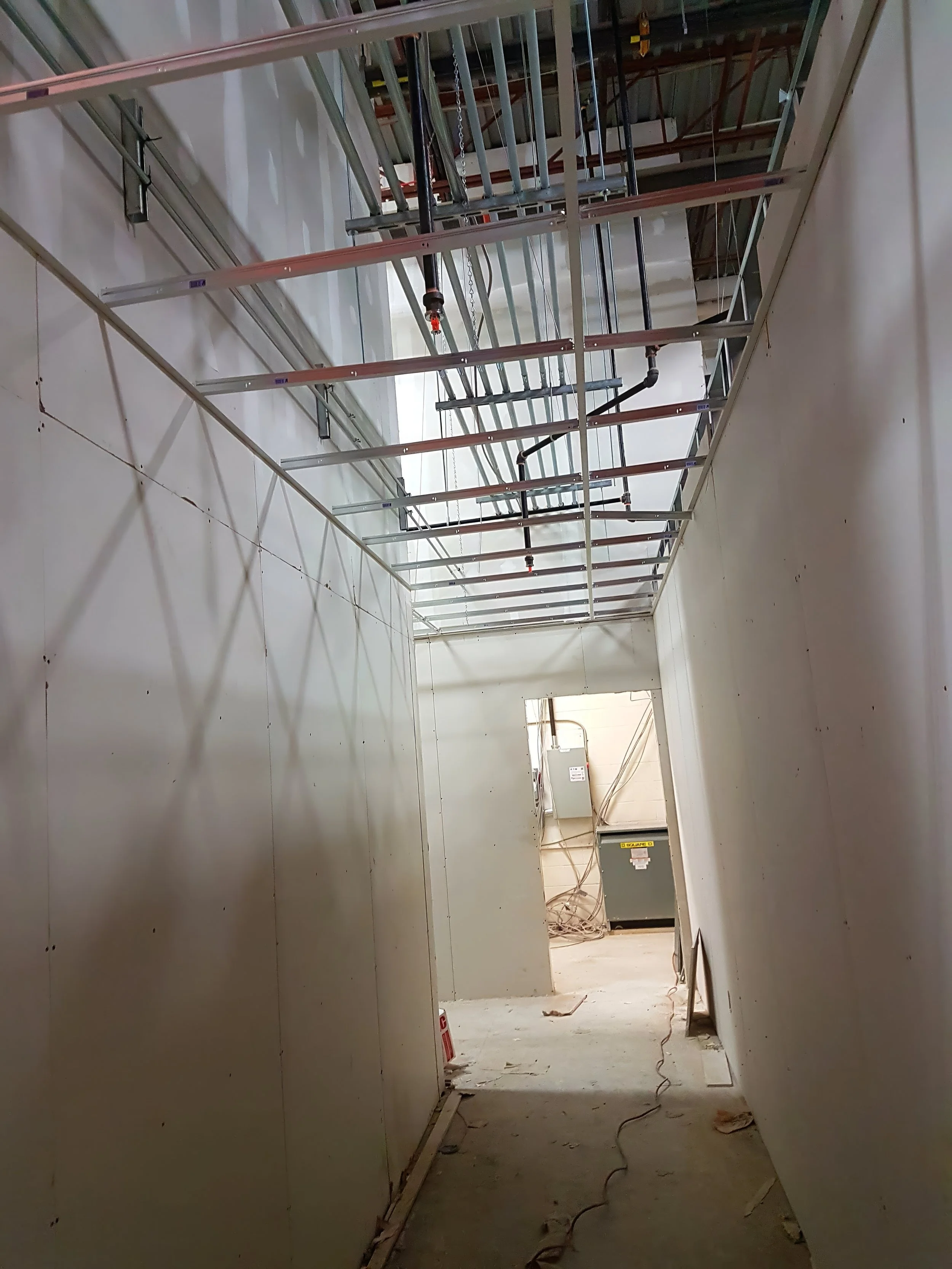 Commercial corridor construction with drywall partition walls and suspended ceiling grid installation in a warehouse renovation project in Toronto