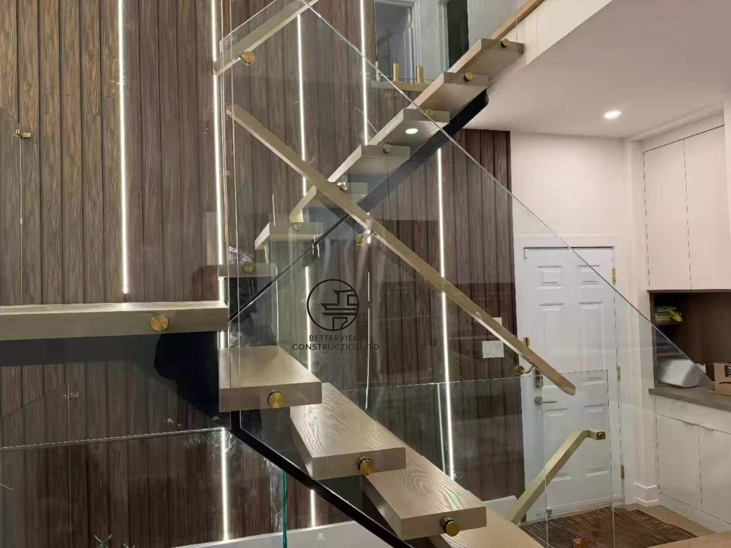 close up of modern floating staircase with glass railing metal supports and wood slat feature wall in Toronto home renovation