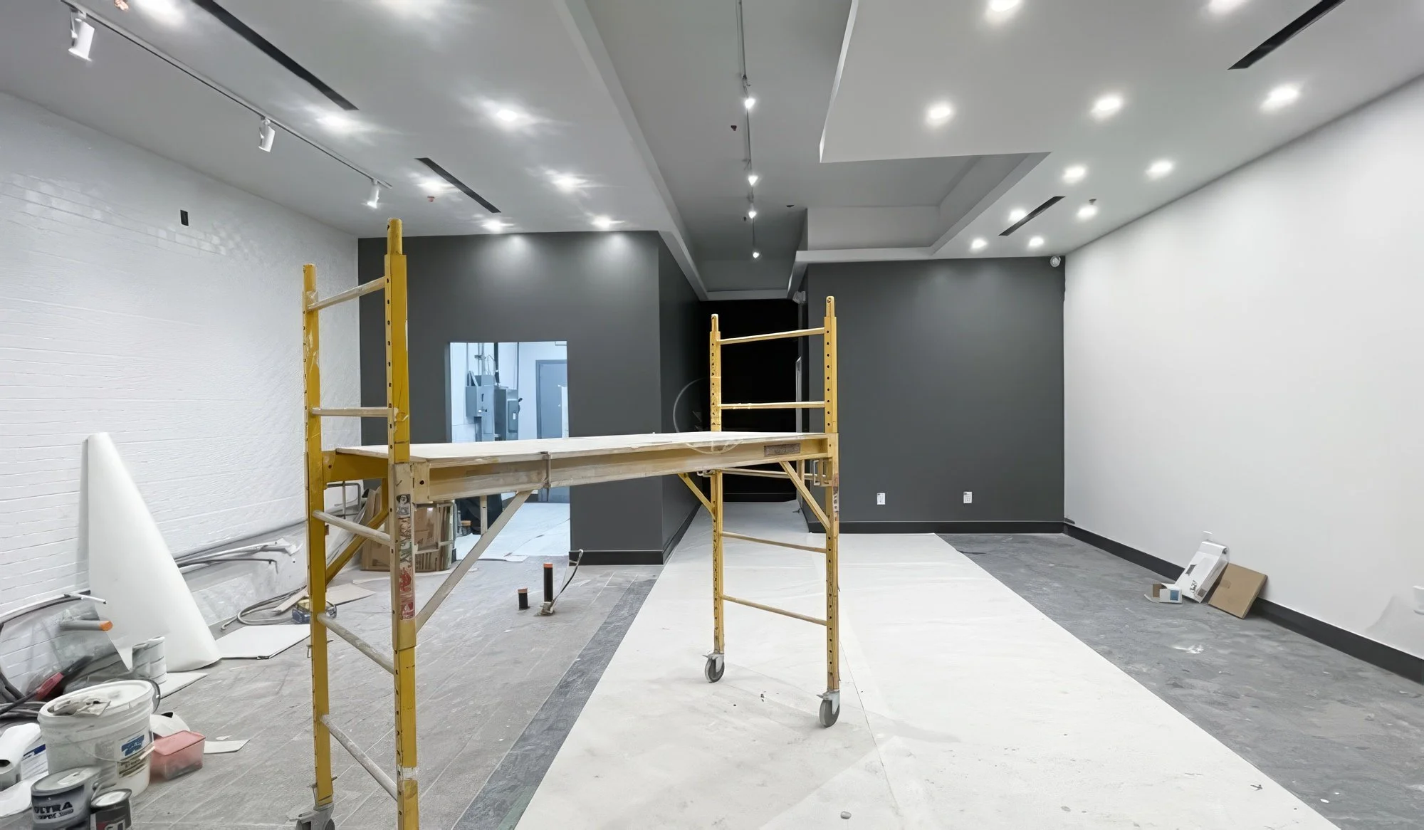 Commercial retail renovation in progress in Toronto showing construction site with scaffolding, lighting installation, and interior build-out work