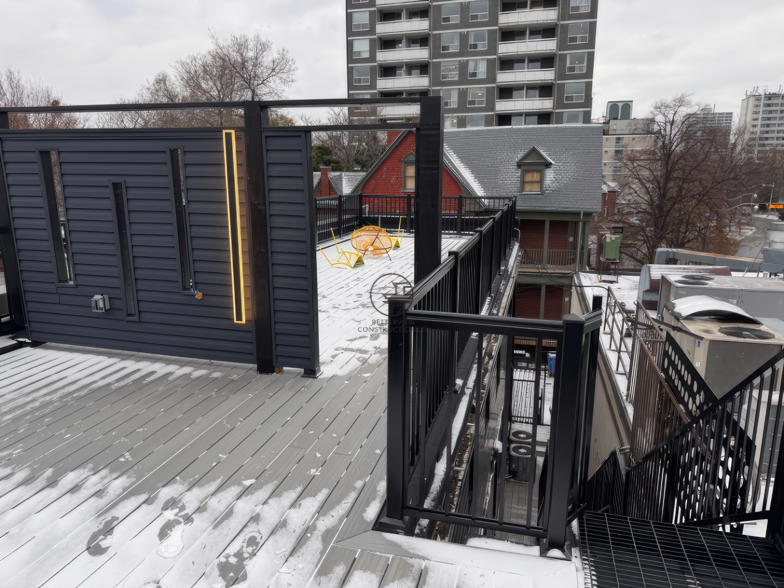 modern rooftop deck with privacy wall, LED lighting, metal staircase, and composite decking in winter