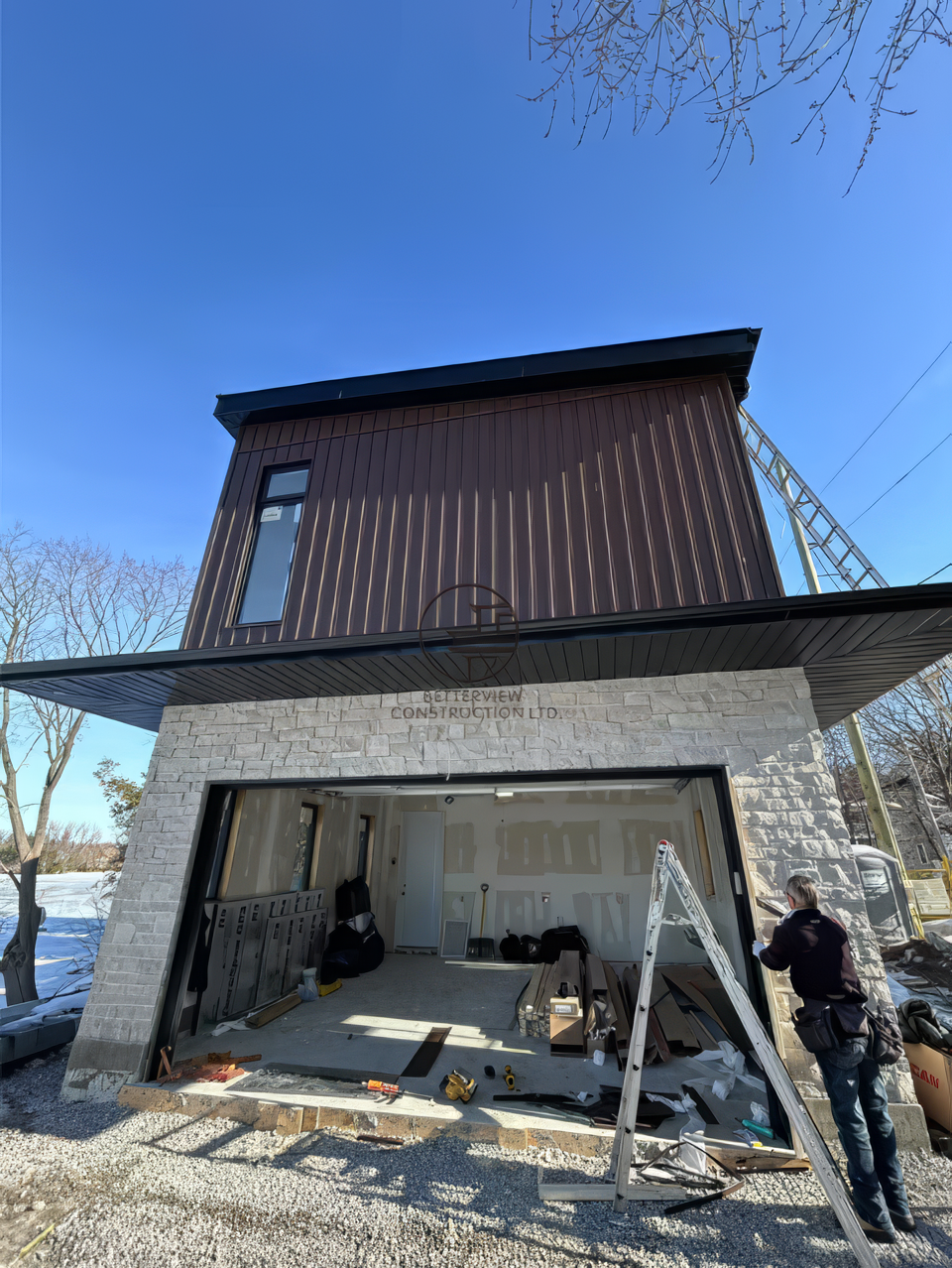 Modern home renovation with large sliding door opening, wood siding and stone facade exterior under construction