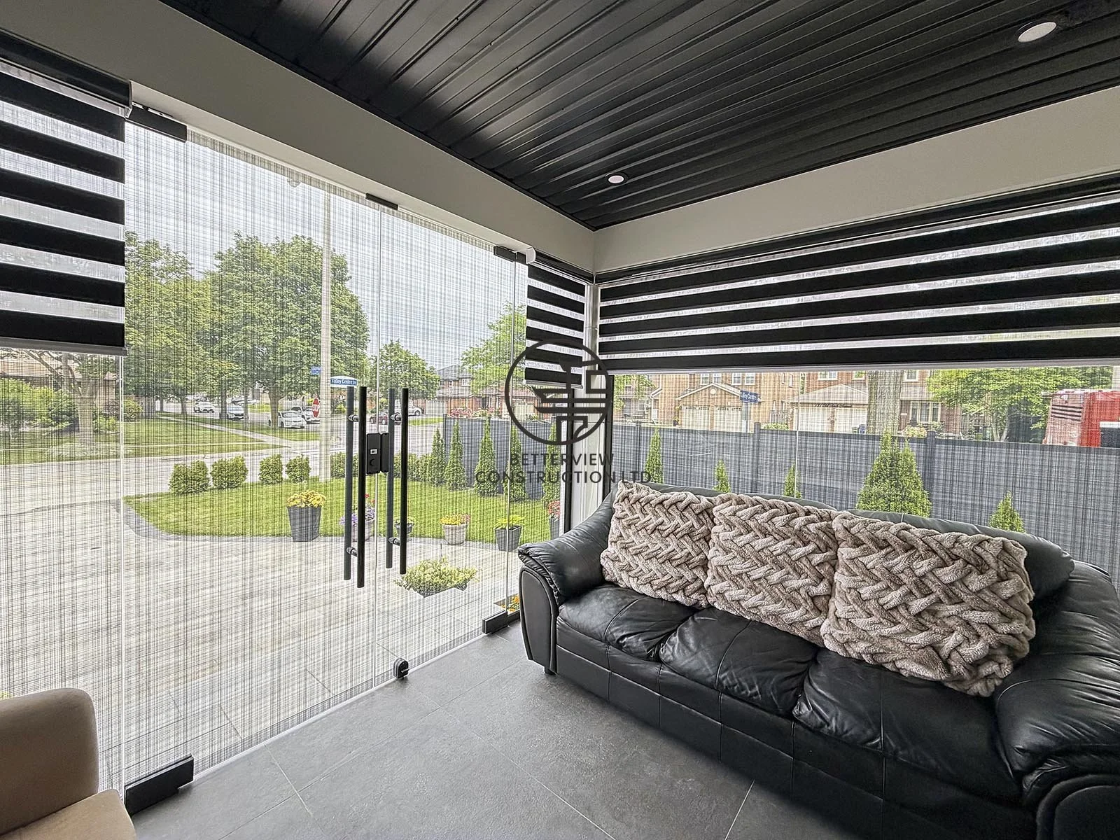 This enclosed front sitting area was built as part of the home addition project, creating a bright and comfortable space that connects indoor and outdoor living. Large glass panels, modern privacy shades, and contemporary finishes maximize natural li