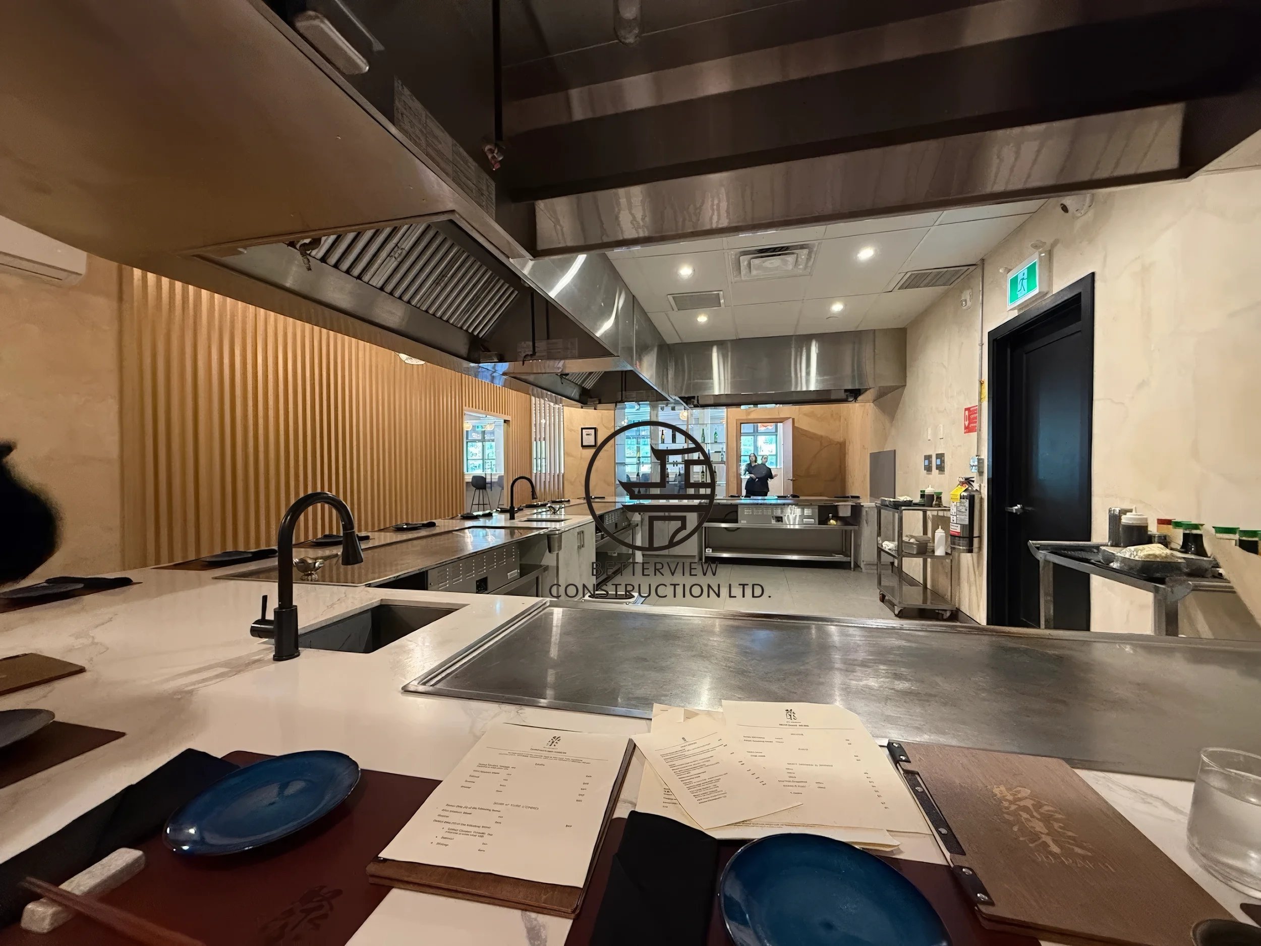 Modern restaurant open kitchen design in Toronto featuring custom countertop, stainless steel commercial kitchen equipment, and completed renovation by contractor