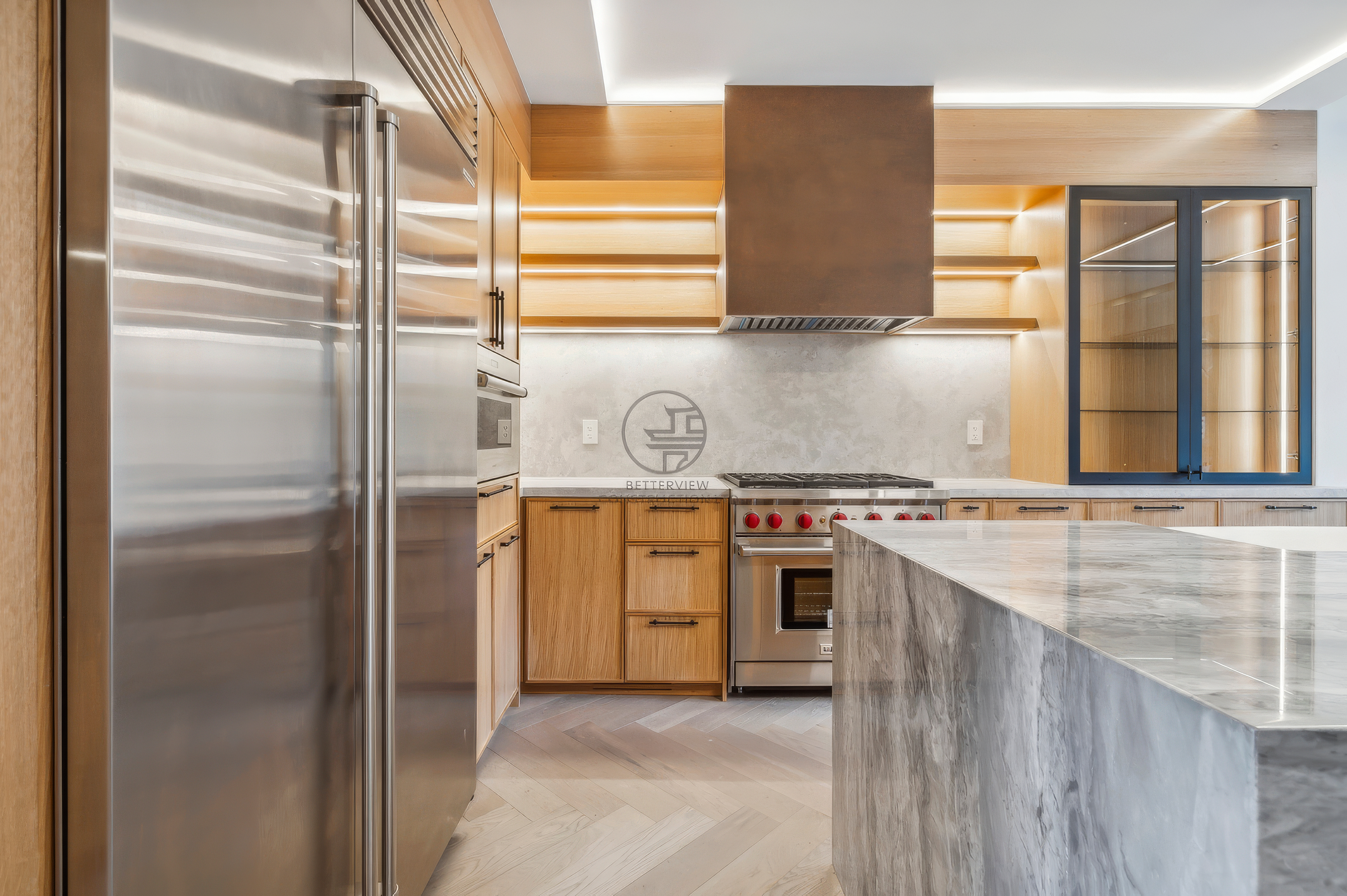 Modern kitchen with wood cabinetry, stainless steel appliances, marble island countertop, open shelving, and warm LED accent lighting.