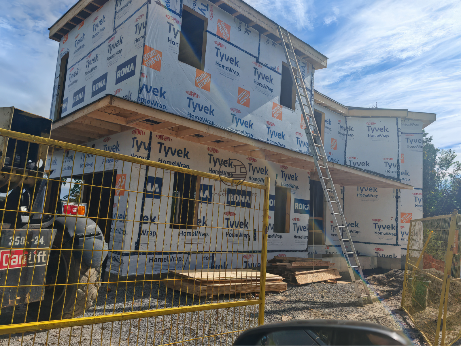 New home construction exterior with Tyvek house wrap, second floor addition and scaffolding in progress