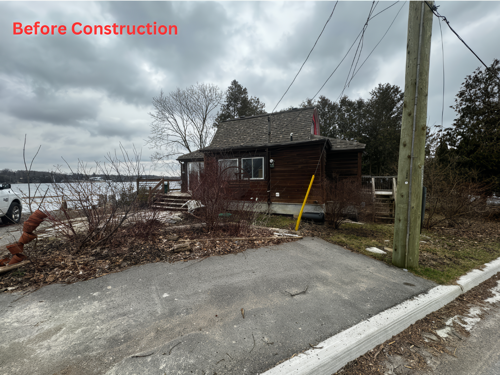 Before construction view of lakeside house exterior with driveway, yard, and surrounding landscape