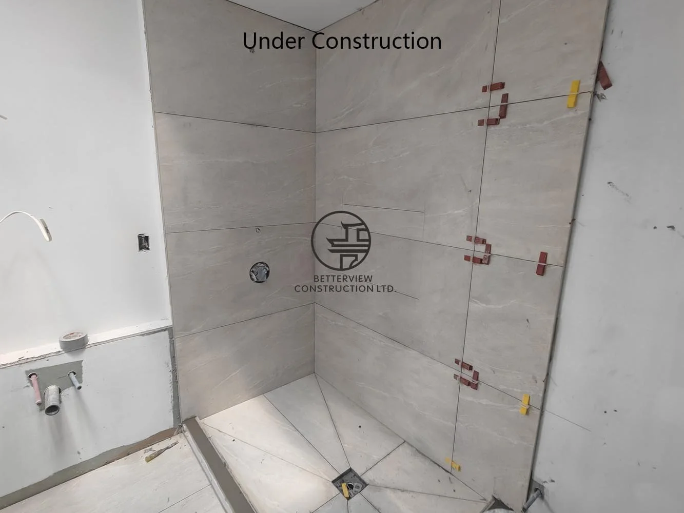 Walk-in shower under construction featuring large-format porcelain tile and preparation for premium bathroom fixtures.
