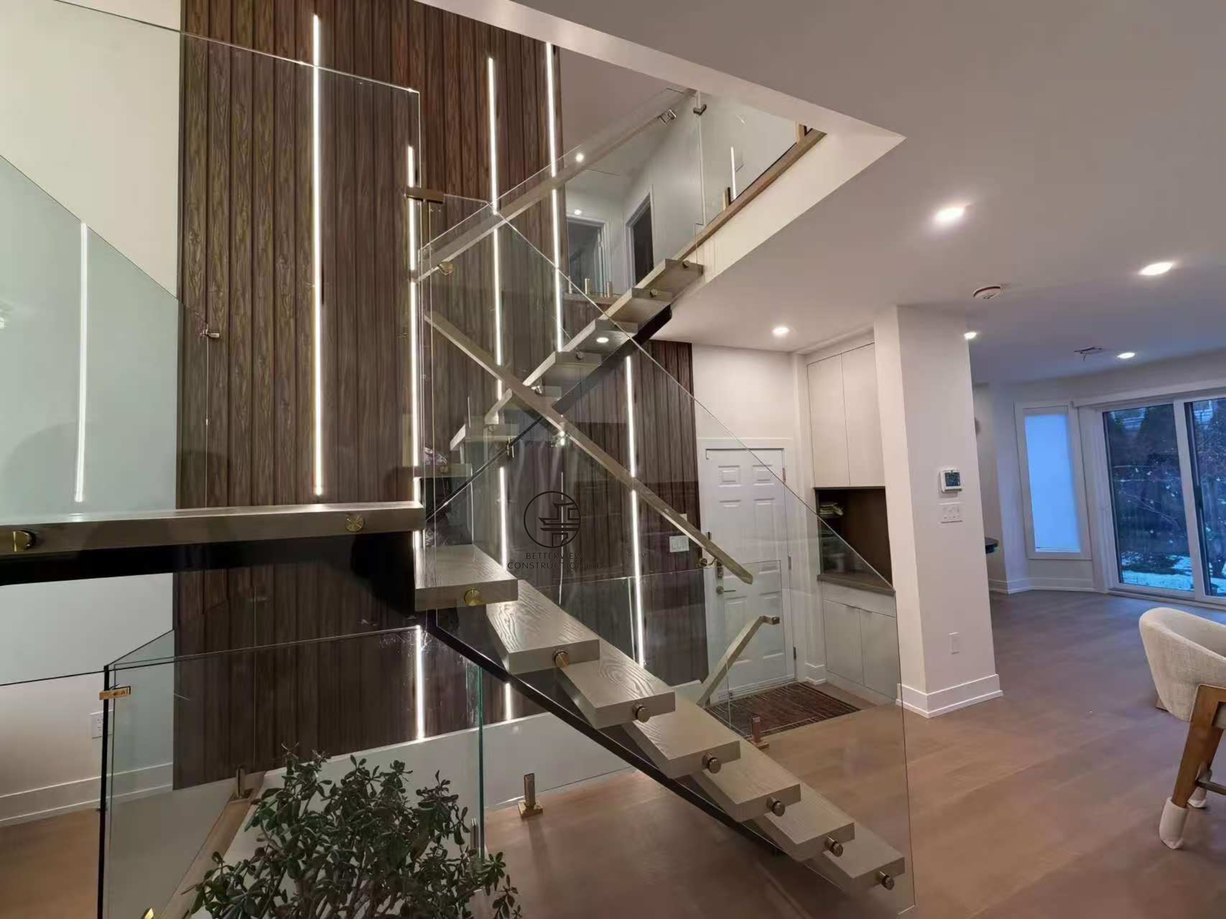 modern floating staircase with glass railing wood accent wall and open concept living space in luxury Toronto home renovation