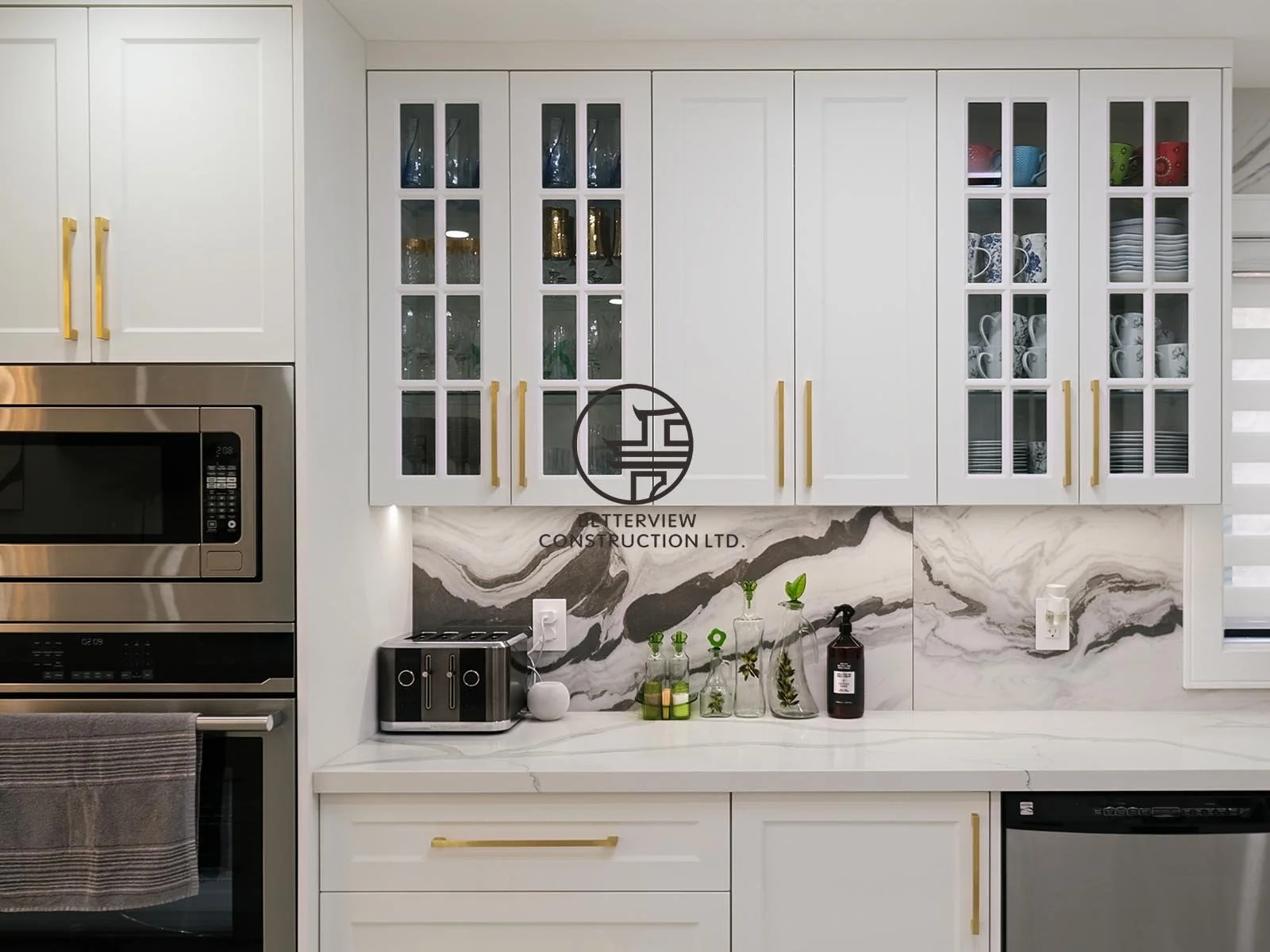 The custom kitchen features white shaker cabinetry, glass display cabinets, quartz countertops, and full-height marble-look backsplash, combining timeless style with everyday functionality.