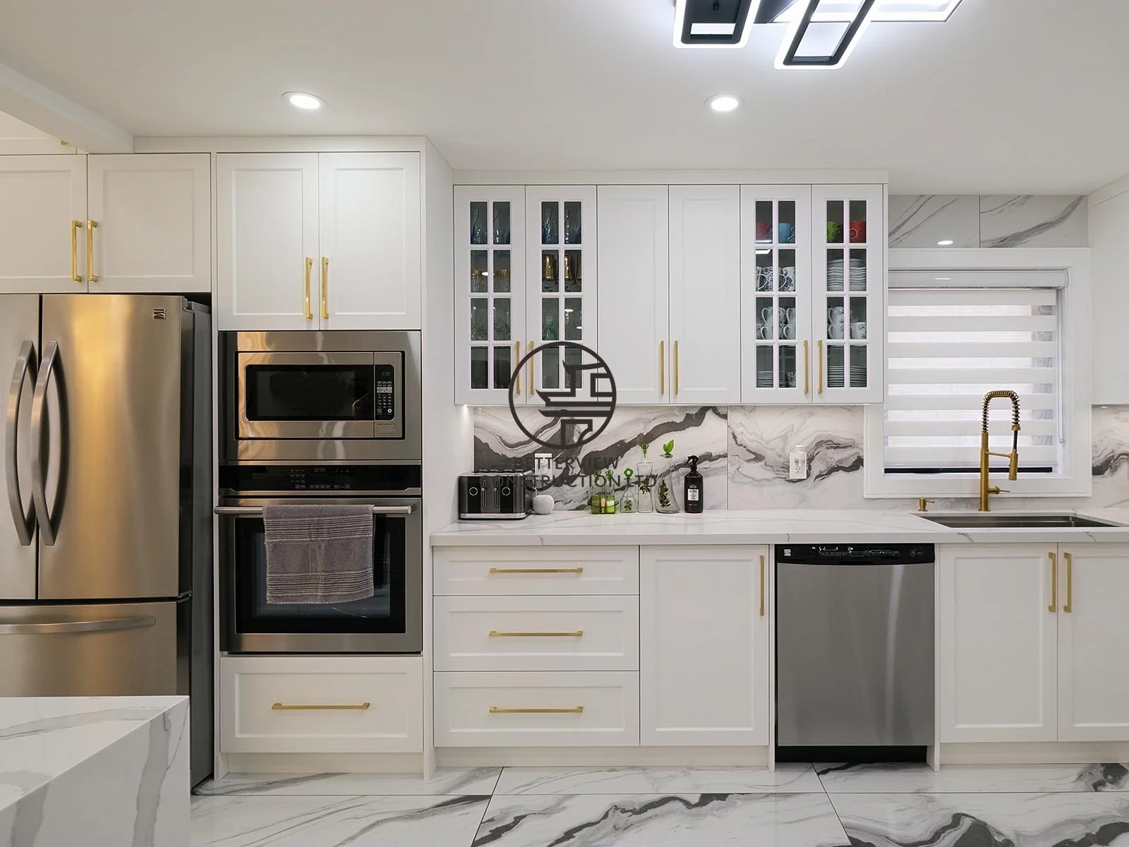 The custom kitchen features white shaker cabinetry, glass display cabinets, quartz countertops, and full-height marble-look backsplash, combining timeless style with everyday functionality.