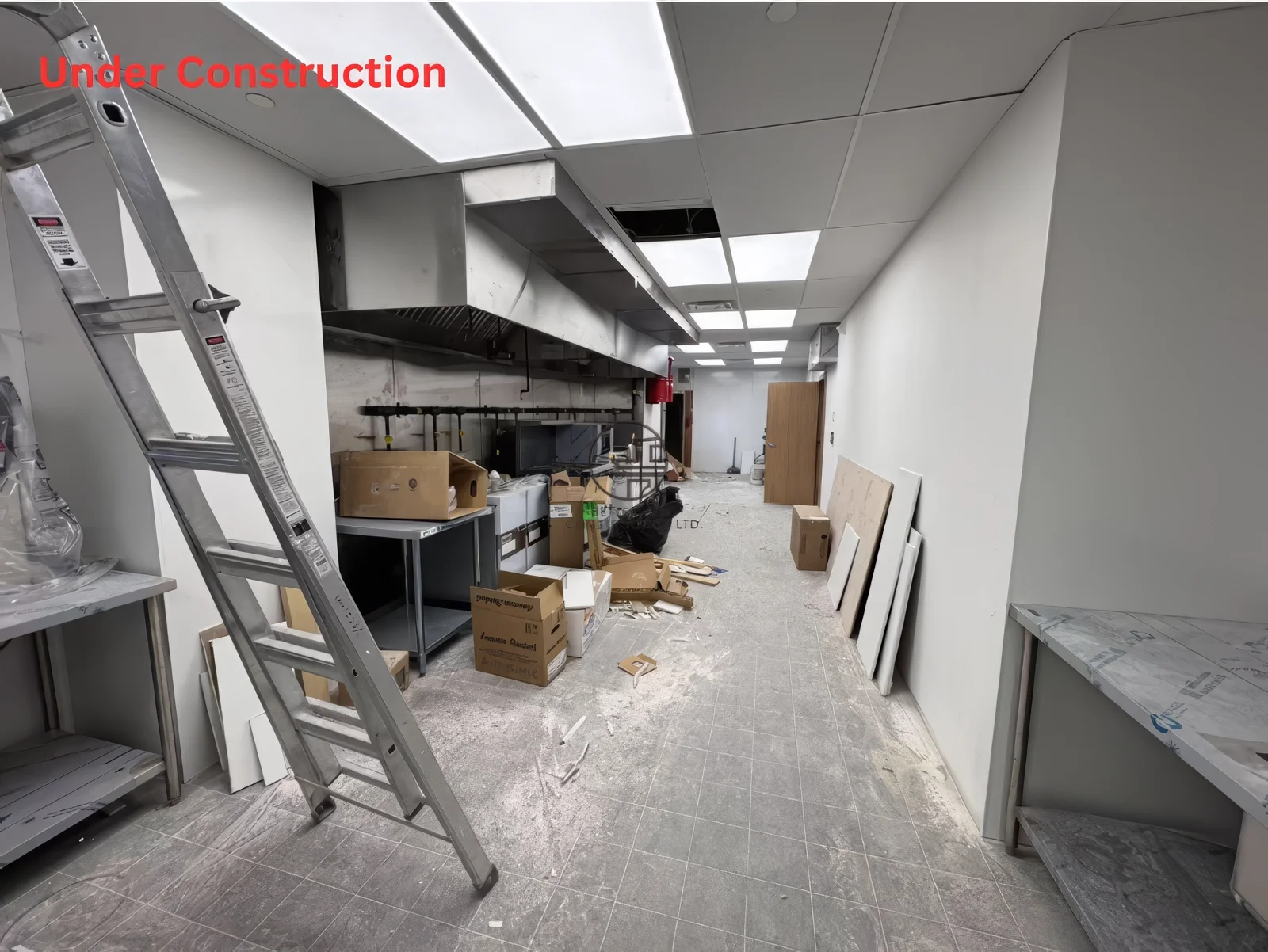 Restaurant commercial kitchen renovation in Toronto featuring ventilation hood installation, stainless steel prep area, and ongoing construction work