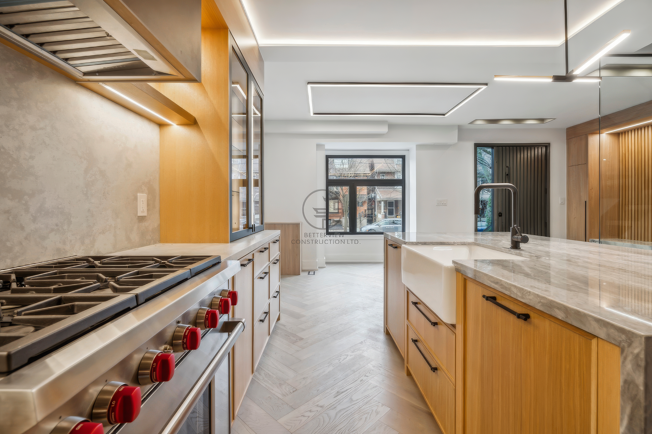 Modern kitchen with gas range, marble island countertop, wood cabinetry, LED ceiling lighting, and open layout in contemporary home design.