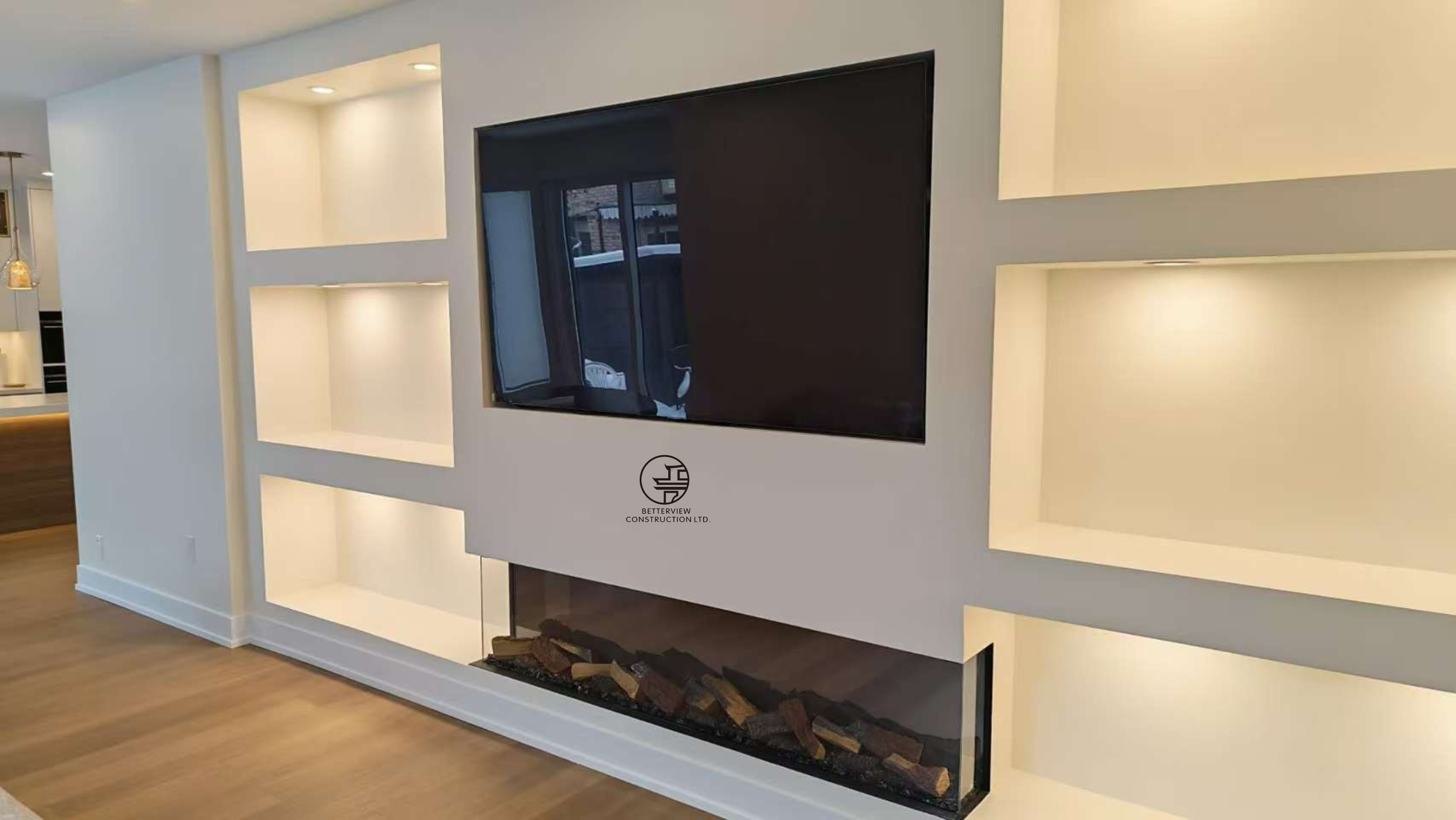 modern built in wall unit with fireplace and TV niche illuminated shelving and clean white finish in Toronto home renovation